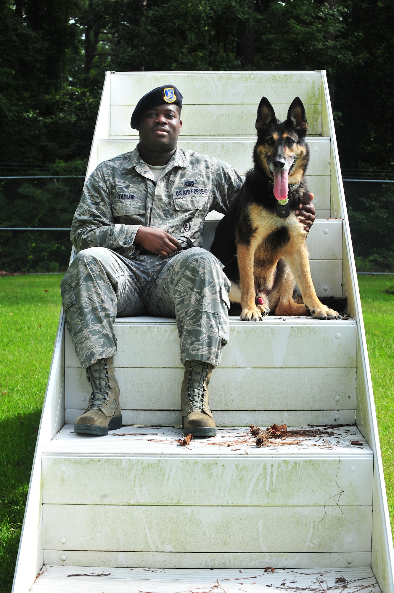 U.S. Air Force Senior Airman Rayshawn Taylor, 4th Security Forces Squadron Military Working Dog (MWD) handler, sits with his dog Charlie, 4th SFS MWD, at Seymour Johnson Air Force Base, N.C., Aug. 21, 2013. Charlie, a 10-year-old German Shepherd and Purple Heart recipient, was retired from active duty after 10 years of service. (U.S. Air Force photo by Senior Airman Aubrey White/Released)
