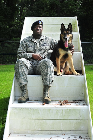 U.S. Air Force Senior Airman Rayshawn Taylor, 4th Security Forces Squadron Military Working Dog (MWD) handler, sits with his dog Charlie, 4th SFS MWD, at Seymour Johnson Air Force Base, N.C., Aug. 21, 2013. Charlie, a 10-year-old German Shepherd and Purple Heart recipient, was retired from active duty after 10 years of service. (U.S. Air Force photo by Senior Airman Aubrey White/Released)