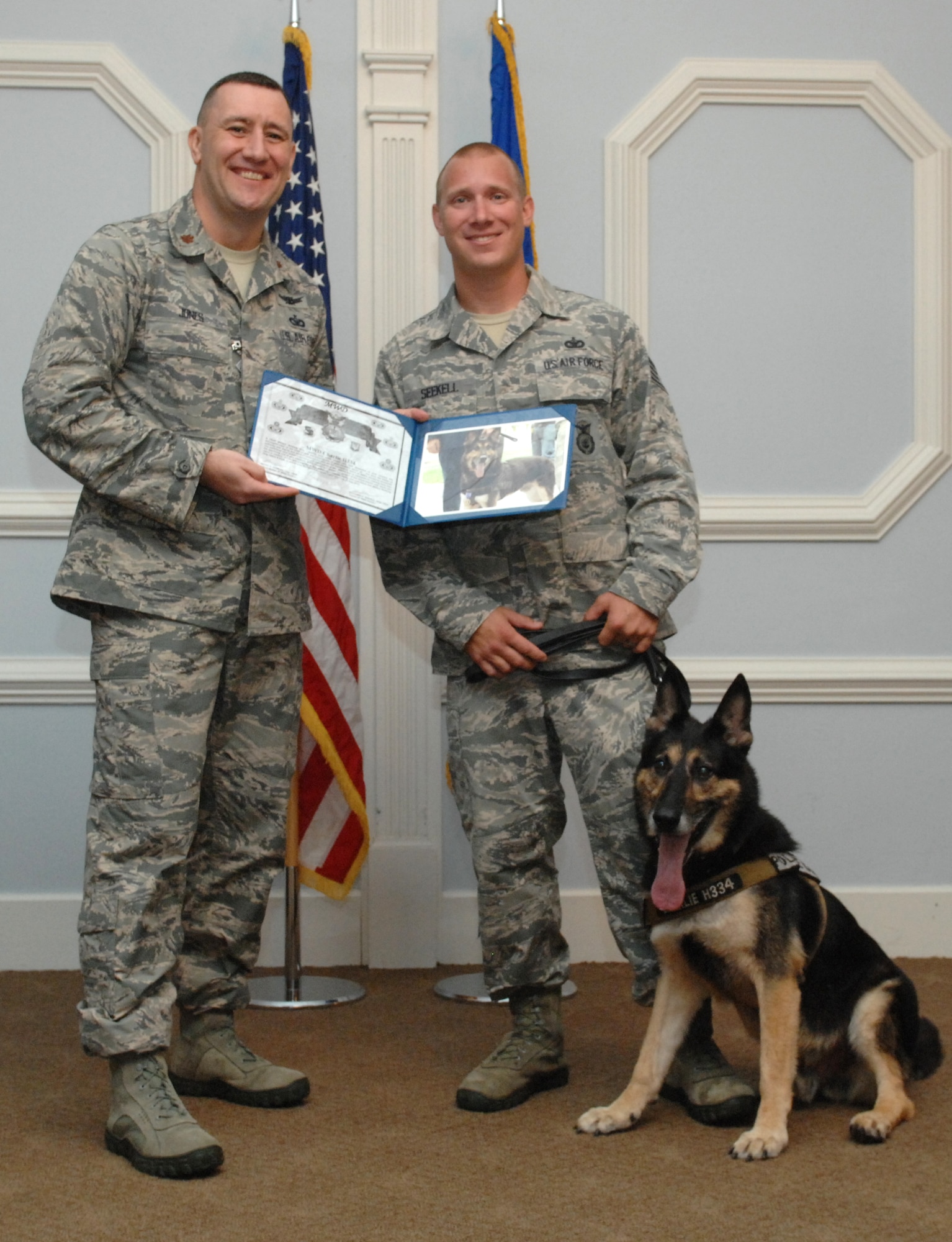 U.S. Air Force Maj. Troy Jones, 4th Security Forces Squadron commander, presents a certificate to Staff Sgt. Benjamin Seekell, 4th SFS Military Working Dog (MWD) trainer and Charlie, 4th SFS MWD, during a retirement ceremony at Seymour Johnson Air Force Base, N.C., Aug. 23, 2013. After 10 years of military service, Charlie was retired and Seekell will adopt him once he is officially released from the Air Force. (U.S. Air Force photo by Airman 1st Class Brittain Crolley/Released)