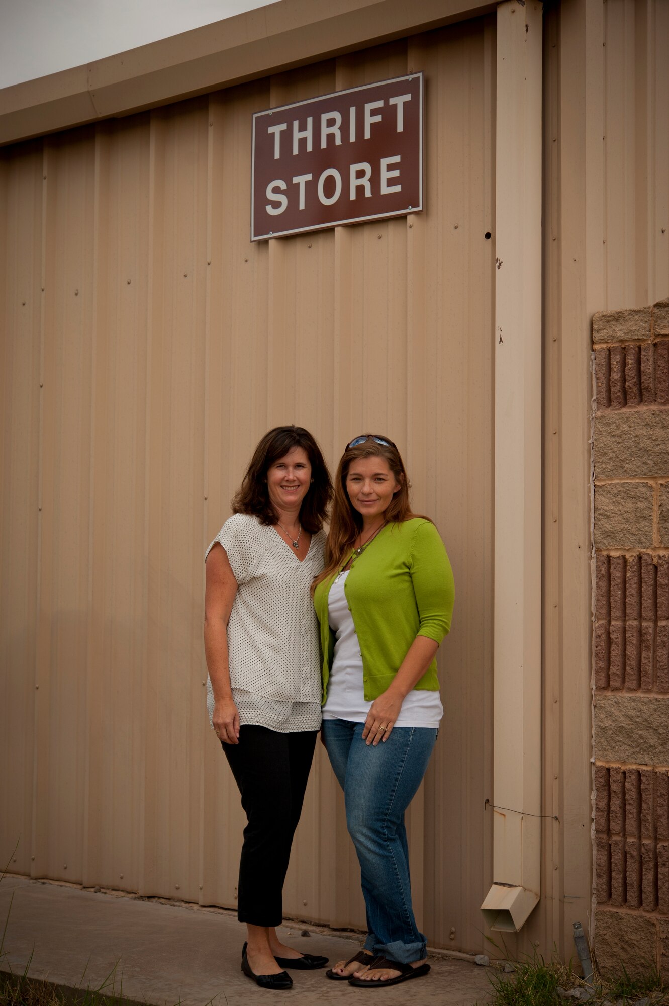 Tracy Patton, wife of Lt. Col. Jeff Patton, 9th Attack Squadron commander, and Carrie, wife of Maj. James, 6th Reconnaissance Squadron pilot, pose prior to opening the Thrift Shop for the 2013 summer season at Holloman Air Force Base, N.M., Aug. 20. The Thrift Shop provides members of Team Holloman a means of acquiring new and gently-used goods at a portion of the cost of the item’s retail value. Last name withheld due to operational safety constraints. (U.S. Air Force photo by Airman 1st Class Aaron Montoya/Released)
