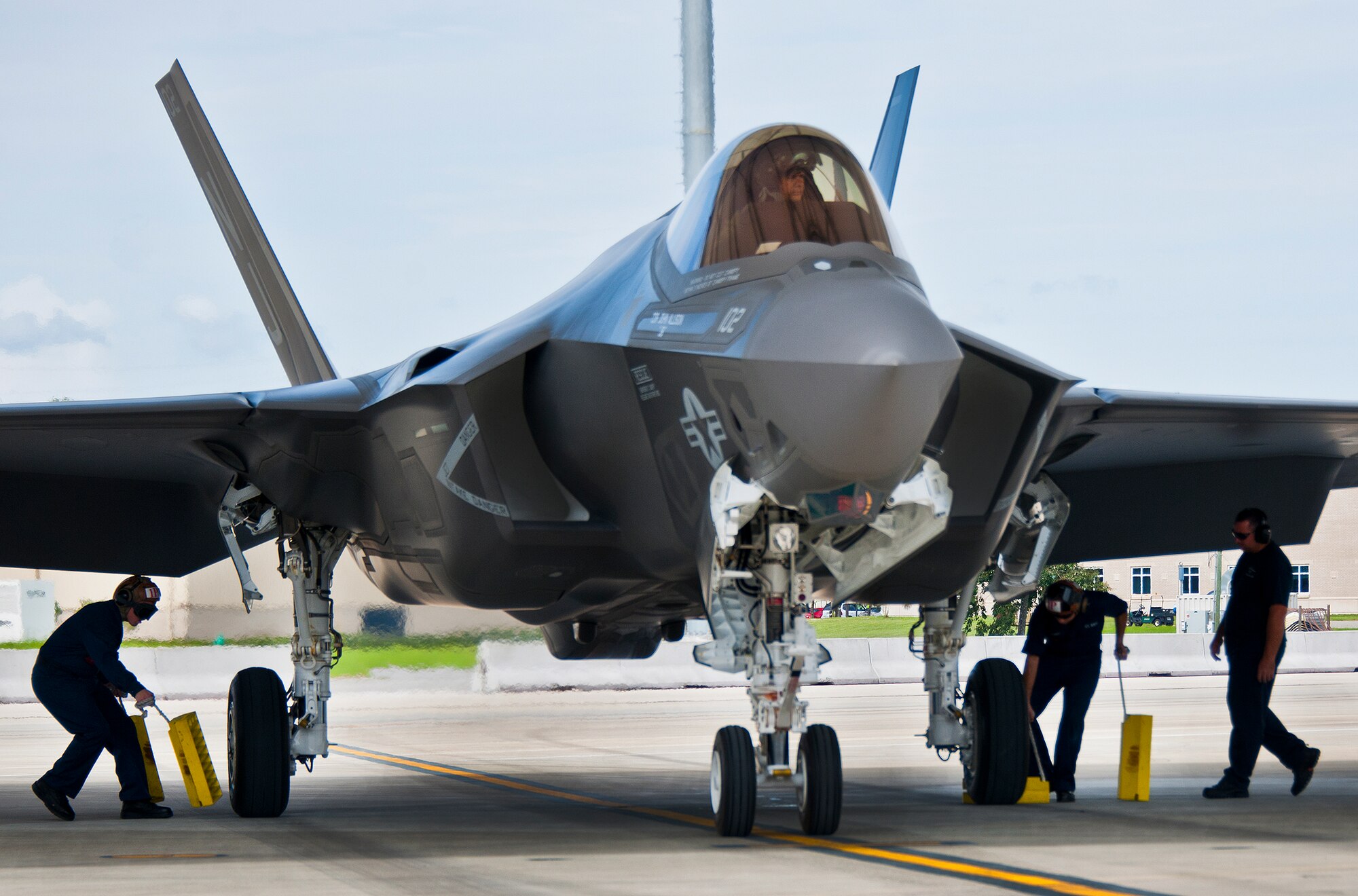 Sailors and Lockheed Martin personnel move in to chock the wheels of a Navy variant F-35C Lightning II after a sortie at Eglin Air Force Base, Fla.  The Sailors from the Strike Fighter Squadron-101, along with Airmen and Marines work directly with the LM maintainers to help put the joint strike fighters in the air.  (U.S. Air Force photo/Samuel King Jr.)