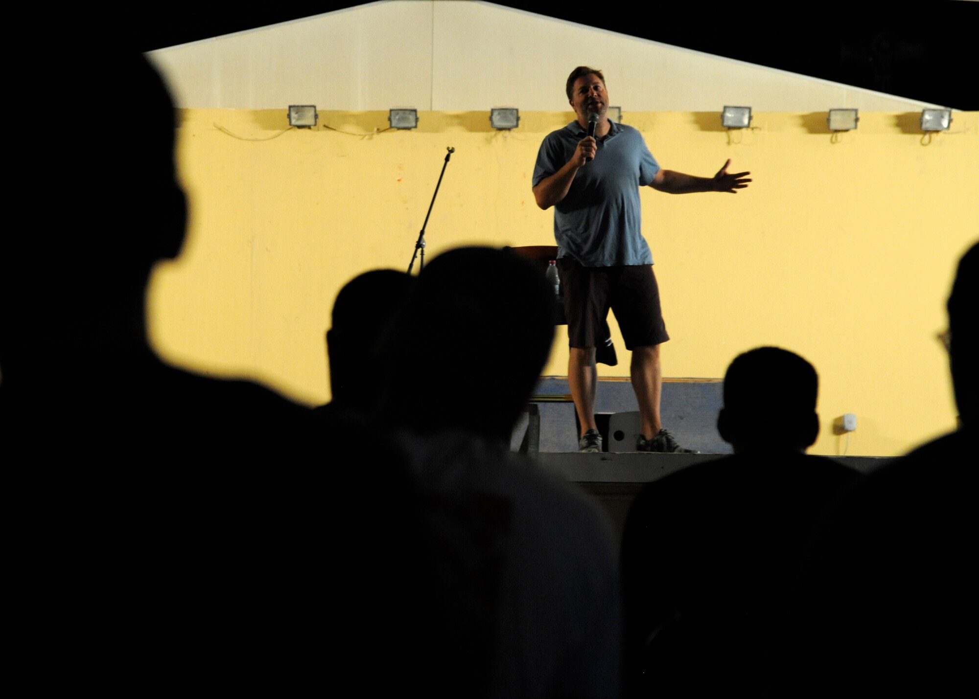 A Grand Slam audience looks on as comedian Jay Larson tells jokes during a comedy tour at the 379th Air Expeditionary Wing in Southwest Asia, Aug. 25, 2013. The 379th Expeditionary Force Support Squadron hosts performers in an effort to regenerate morale in the deployed location. (U.S. Air Force photo/Senior Airman Bahja J. Jones) 