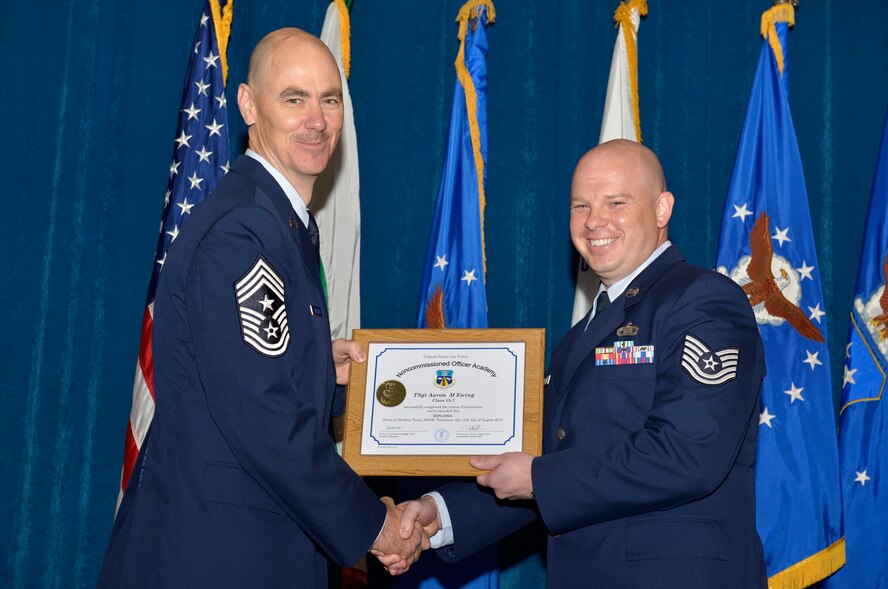 McGHEE TYSON AIR NATIONAL GUARD BASE, Tenn. - Tech. Sgt. Aaron M. Ewing, right, from Shaw AFB, receives the distinguished graduate award for Noncommissioned Officer Academy Class 13-7 from Chief Master Sgt. Ronald C. Anderson, Jr., 1st Air Force (Air Forces Northern), Tyndall Air Force Base, Fla. here, Aug. 15, 2013 The distinguished graduate award is presented to students in the top 10 percent of the class.  It is based on objective and performance evaluations, demonstrated leadership, and performance as a team player. (U.S. Air National Guard photo by Master Sgt. Kurt Skoglund/Released)