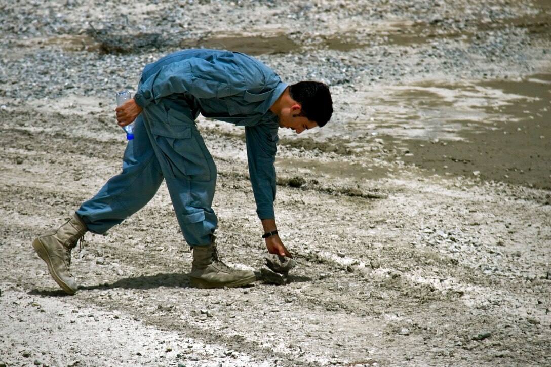 An Afghan uniformed policeman stacks up rocks to mark a potential improvised explosive device emplacement during a class on Forward Operating Base Salerno in Khowst province, Afghanistan, Aug. 18, 2013.