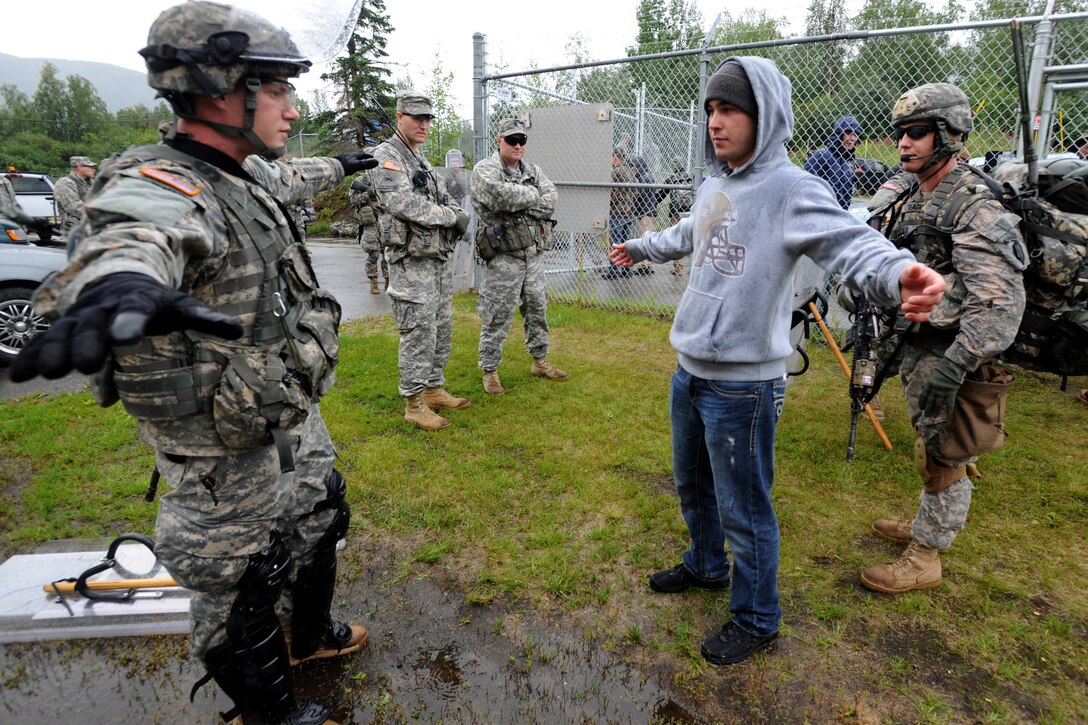Army Pfc. Travis Watson, left, and Army Staff Sgt. Homer Teague, right, search a soldier playing the part of a local leader during a natural disaster exercise on Joint Base Elmendorf-Richardson, Alaska, Aug. 19, 2013. Watson and Teague are assigned to the 1st Squadron Airborne, 40th Cavalry Regiment.