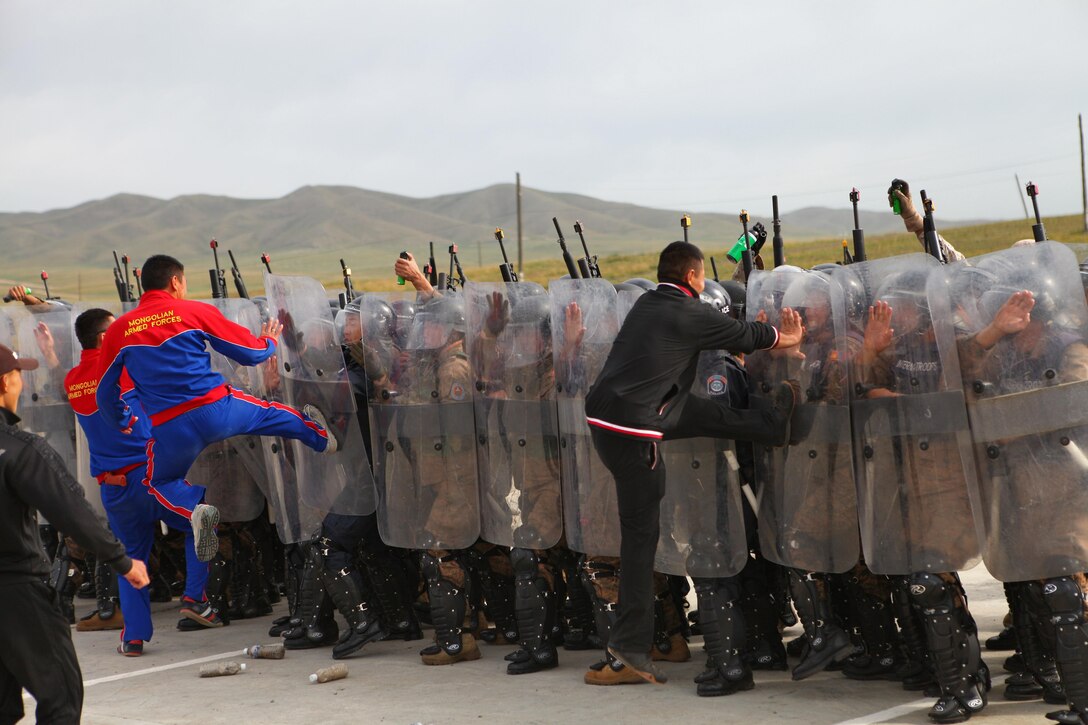 Mock rioters turn into agressors during a non-lethal tactics demonstration at Five Hills Training Area, Mongolia, Aug. 26. The event included a ceremony that marked the conclusion of the field training exercise and start of the leadership portion during the Non-Lethal Weapons Executive Seminar. NOLES is hosted annually in the Pacific region and led this year by U.S. Marines with 3rd Law Enforcement Battalion, III Marine Expeditionary Force. Mongolia, a regular participant, is hosting NOLES for the third time in 12 years.