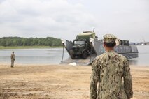 A sailor with the Navy's Beach Departure Team 5 watches over a Marine with Combat Logistics Battalion 24, 2nd Marine Logistics Group as he loads a Medium Tactical Vehicle Replacement onto a Landing Craft Utility aboard Naval Amphibious Base Little Creek, Va., during a Defense Support of Civil Authorities, or DSCA, training exercise, Aug. 21, 2013. The battalion performed loading and offloading exercises in preparation for possible DSCA missions during natural disaster disasters.