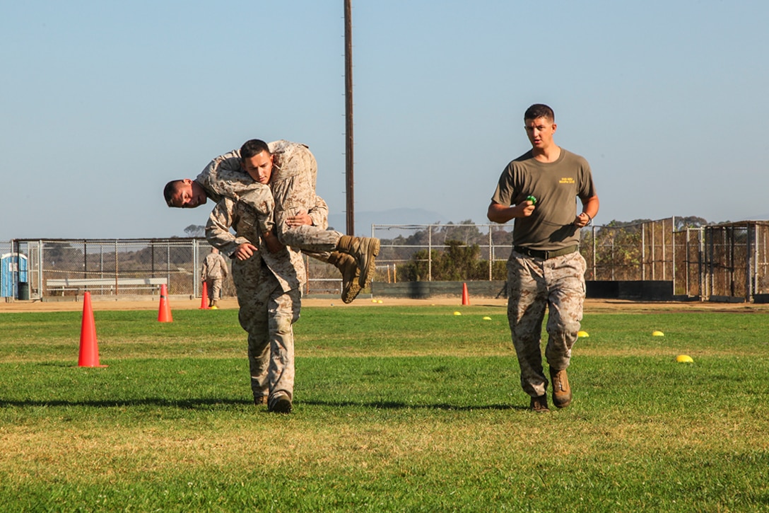 Sergeant Daniel Vance, administrative specialist, carries Lance Cpl. Rene Gonzalez, data network specialist, while Cpl. Michael Travis, Marine Air-Ground Task Force planning specialist, all with Command Element, 15th Marine Expeditionary Unit, marks the time hit during a unit Combat Fitness Test aboard Camp Pendleton, Calif., Aug. 21, 2013. Vance, 23, is from Sparta, Ky., Gonzalez, 20, is from Joliet, Ill. and Travis, 25, is from Talladega, Ala. (U.S. Marine Corps Photo by Cpl. Emmanuel Ramos/Released)