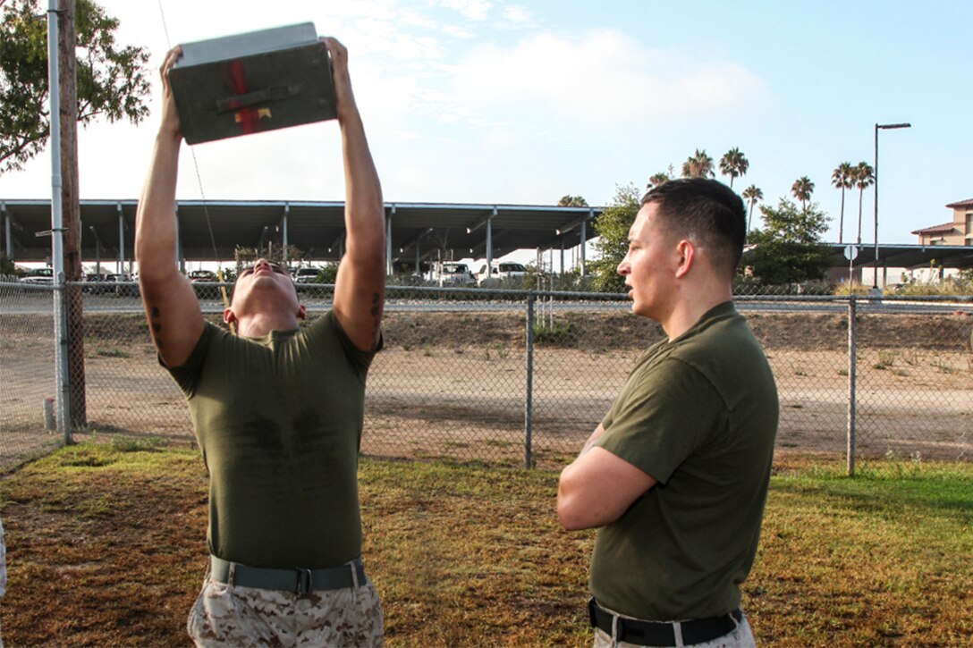 Lance Cpl. Albert Perez III performs ammunition can presses while Sgt. Daniel Vance, both administrative specialists, Command Element, 15th Marine Expeditionary Unit, keeps count of the repetitions during a unit Combat Fitness Test aboard Camp Pendleton, Calif., Aug. 21, 2013. Perez, 21, is from Los Angeles and Vance, 23, is from Sparta, Ky. (U.S. Marine Corps Photo by Cpl. Emmanuel Ramos/Released)