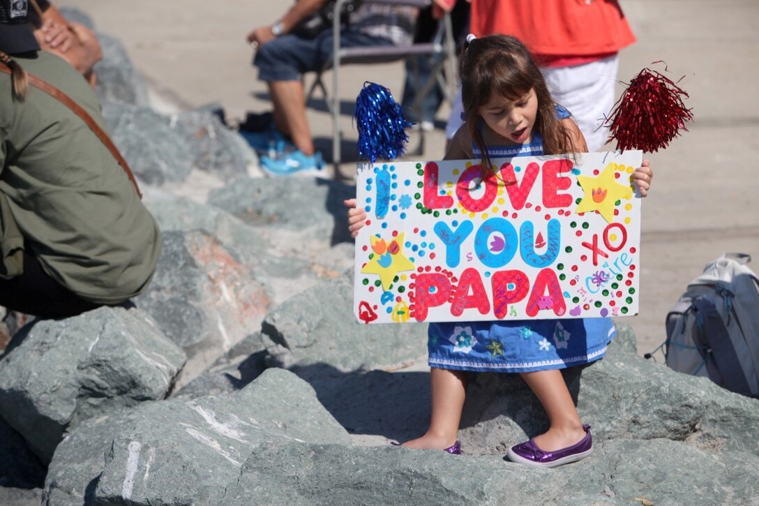 Claire Glenn, 5, holds up the sign she made for her father, Maj. Stuart Glenn, the S-3 officer with the 13th Marine Expeditionary Unit, Aug. 23. Glenn, along with more than 2,400 Marines and sailors with the 13th MEU departed for deployment with the Boxer Amphibious Ready Group.