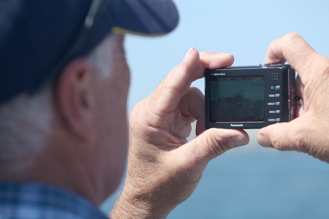 An onlooker photographs the 13th Marine Expeditionary Unit aboard the USS Boxer as it departs for deployment out of Naval Base San Diego, Aug. 23.