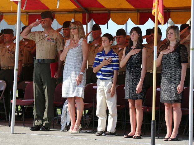 MARINE CORPS BASE CAMP PENDLETON, Calif. – Sergeant Maj. Michael P. Woods, the sergeant major of 3rd Assault Amphibian Battalion, salutes alongside his family as the national anthem is played by the 1st Marine Division Band during a relief and appointment ceremony here, Aug. 23, 2013. During the course of his 21-year career, Woods served with several tank and infantry battalions, completed a tour as a drill instructor and deployed overseas and to combat zones on numerous occasions.