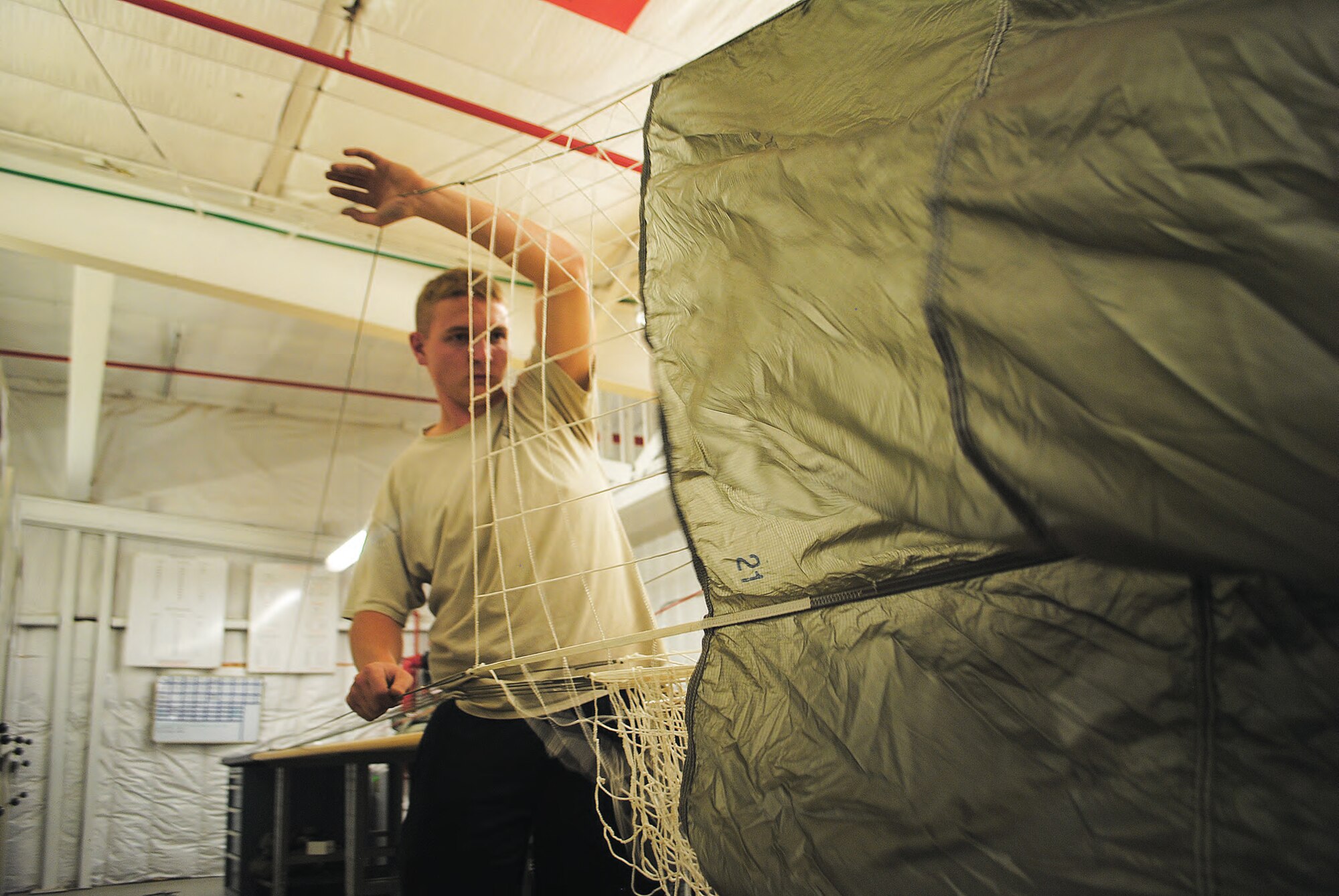 Senior Airman Mitchell Bolyard, parachute rigger, untangles a static-line chute.  (Photo by Jonathan Rejent)