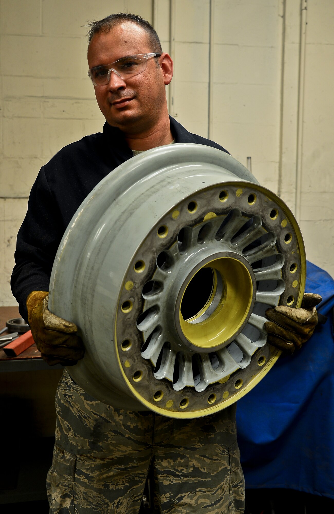 Staff Sgt. Alex Aguayo 6th Maintenance Squadron aircraft metals technician displays a KC-135 wheel, Aug 22, 2013 at MacDill Air Force Base, Fla. Aguayo engineered a stand to hold the wheel which reduced the man ours needed to paint by 26 hours per set. (U.S. Air Force photo by Staff Sgt. Brandon Shapiro/Released) 