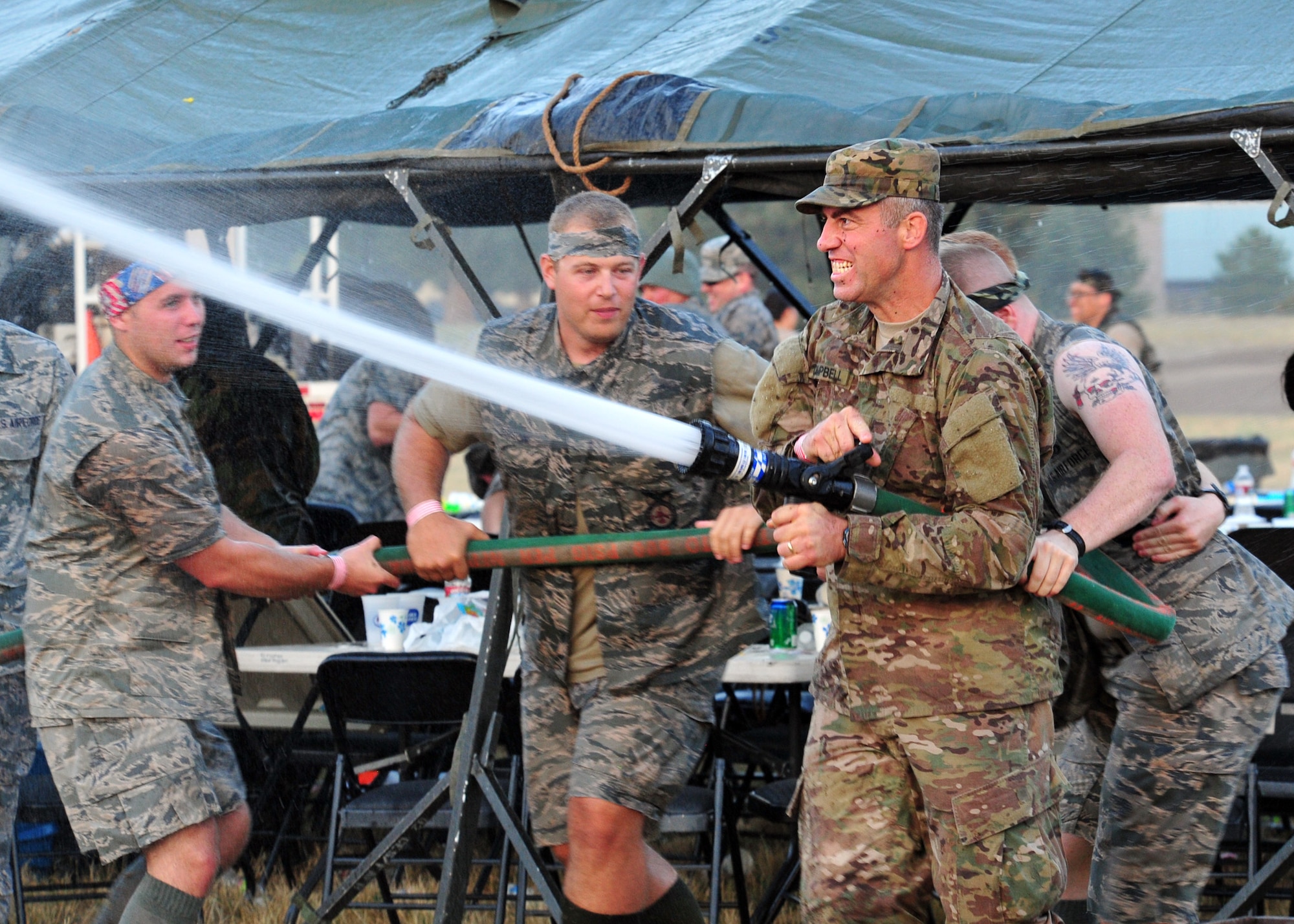 Members of Team Fairchild engage in a water fight using water guns, balloons and hoses during the Combat Dining In at Fairchild Air Force Base, Wash., Aug. 23, 2013. Members were able to attend wearing any combination of Air Force uniforms including the Airman battle uniform, desert combat uniform, battle dress uniform and even flight suits. (U.S. Air Force photo by Senior Airman Taylor Curry/Released)