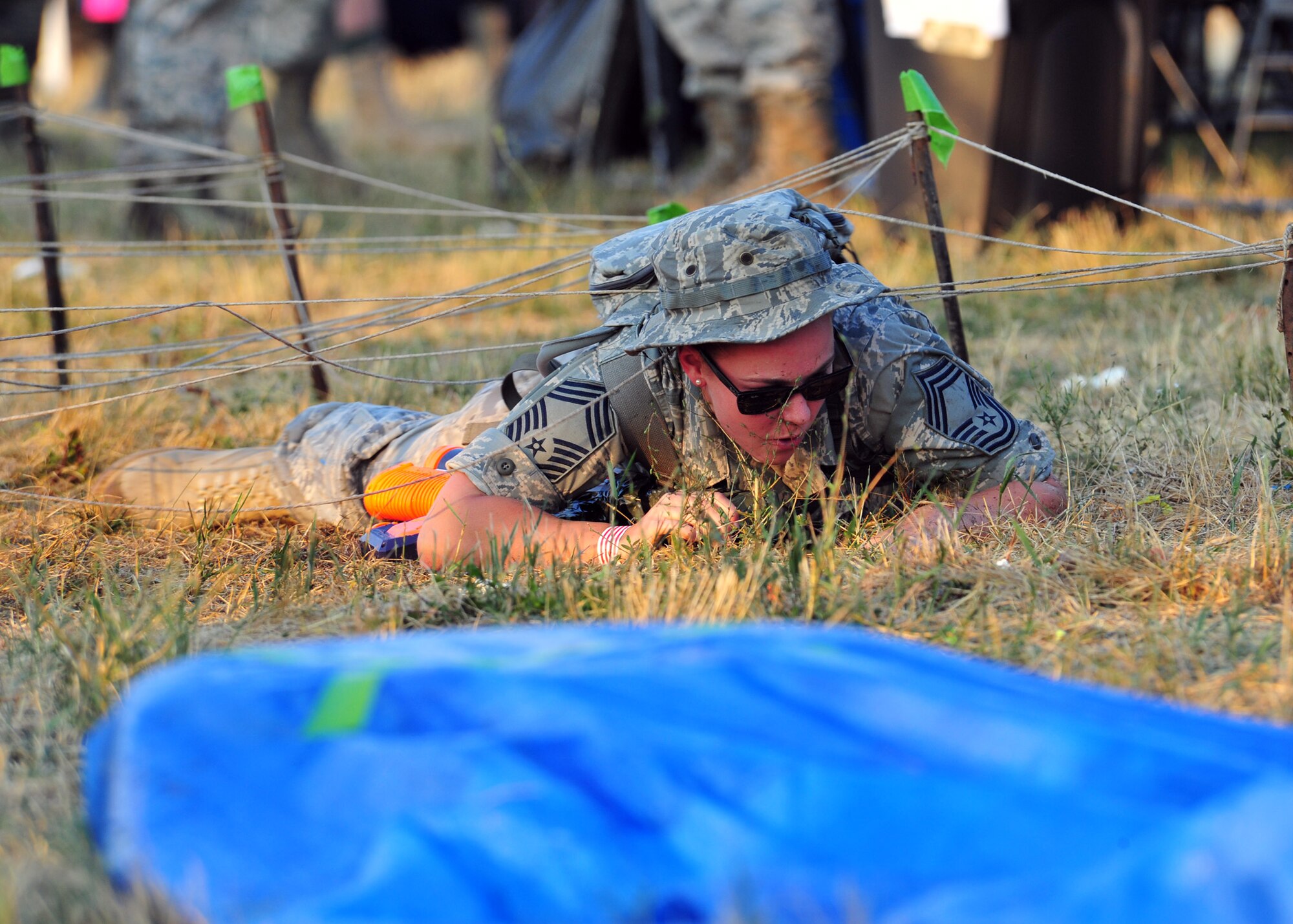 Senior Airman Candace Goldfuss, 92nd Security Forces Squadron installation patrolman, performs the low crawl on the obstacle course during the Combat Dining In at Fairchild Air Force Base, Wash., Aug. 23, 2013. The event was intended to enhance esprit of units and enable military members of all ranks to create bonds of friendship and better working relations. (U.S. Air Force photo by Senior Airman Taylor Curry/Released)