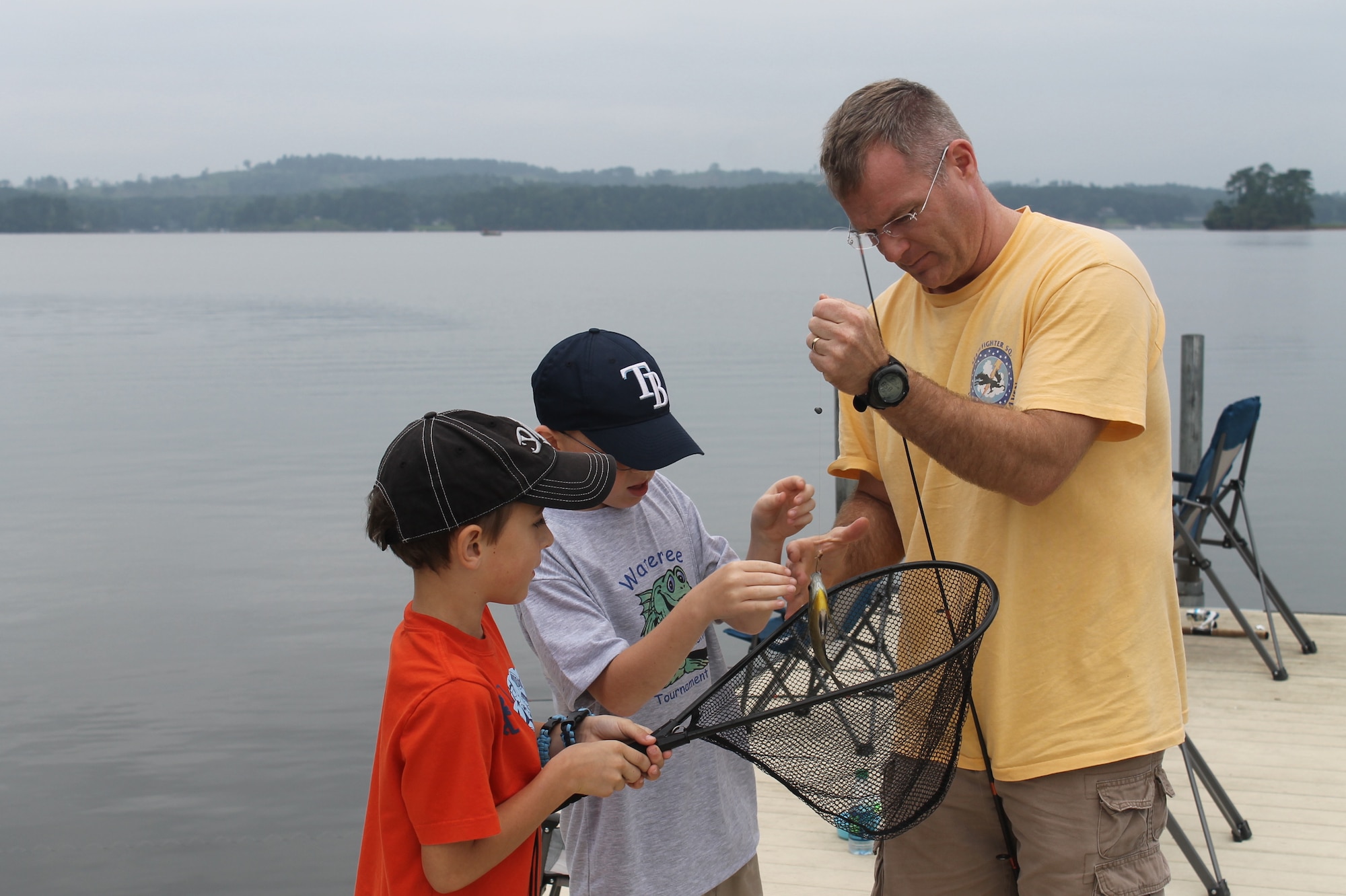 Col. Paul Murray, 20th Operations Group commander, helps two children unhook a fish they caught during the 7th Annual End of Summer Kids Fishing Tournament at the Wateree Recreation Area, S.C., Aug. 24, 2013. (Courtesy photo by Curt Marshall) 