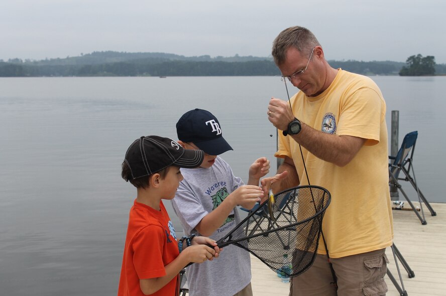 Col. Paul Murray, 20th Operations Group commander, helps two children unhook a fish they caught during the 7th Annual End of Summer Kids Fishing Tournament at the Wateree Recreation Area, S.C., Aug. 24, 2013. (Courtesy photo by Curt Marshall) 
