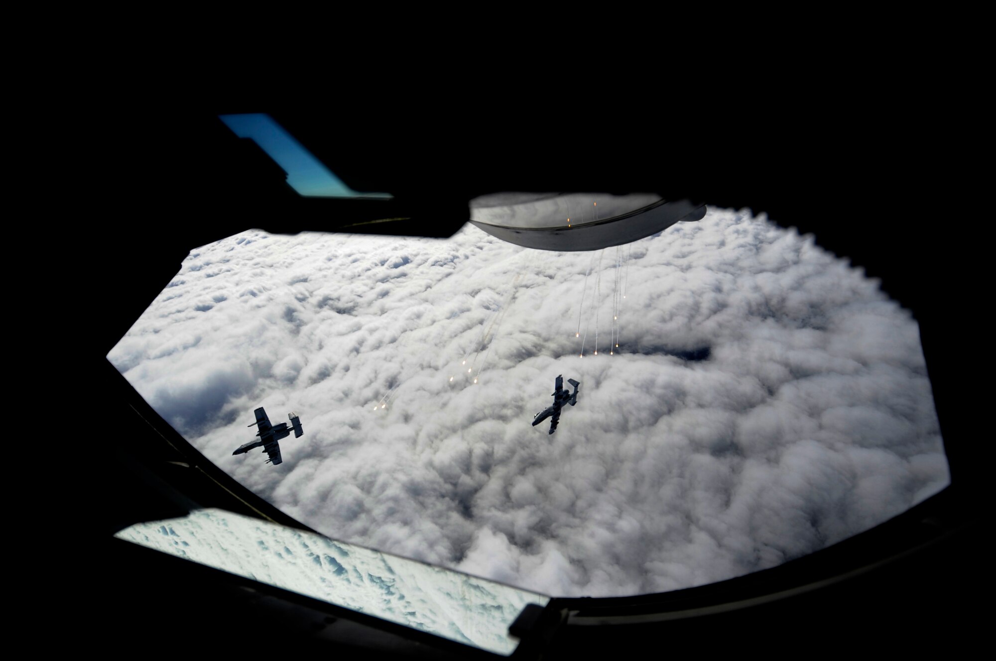 Two A-10 Thunderbolts from the 163rd Fighter Squadron, Indiana Air National Guard, Ft. Wayne, Ind., bank away from a KC-135 Stratotanker and deploy flares over the Joint Pacific Alaska Range Complex after being refueled during RED FLAG-Alaska 13-3, Aug. 21, 2013, Eielson Air Force Base, Alaska. The KC-135 is part of the 909th Air Refueling Squadron, Kadena Air Base Japan. (U.S. Air Force photo by Senior Airman Shawn Nickel/Released)