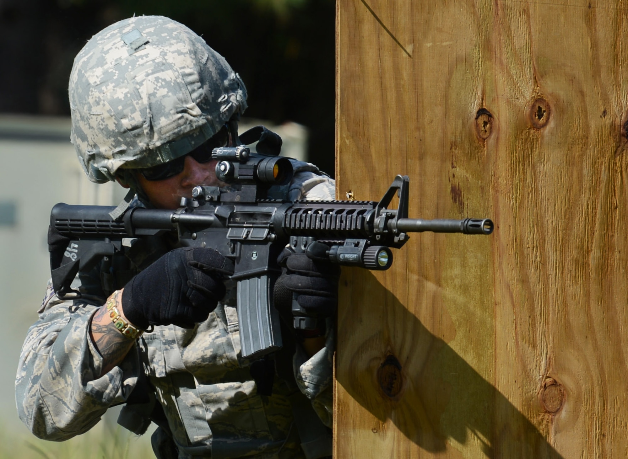 U.S. Air Force Airman 1st Class Mike Garza, 20th Security Forces Squadron patrolman, shoots an M4 carbine from behind a wooden barrier to cover his wingman during a shoot, move and communicate exercise at Shaw Air Force Base, S.C., Aug. 21, 2013. Every six months, 20th SFS Airmen are required to complete M4 carbine sufficiency training while learning to work as a team. (U.S. Air Force photo by Senior Airman Tabatha Zarrella/Released)
