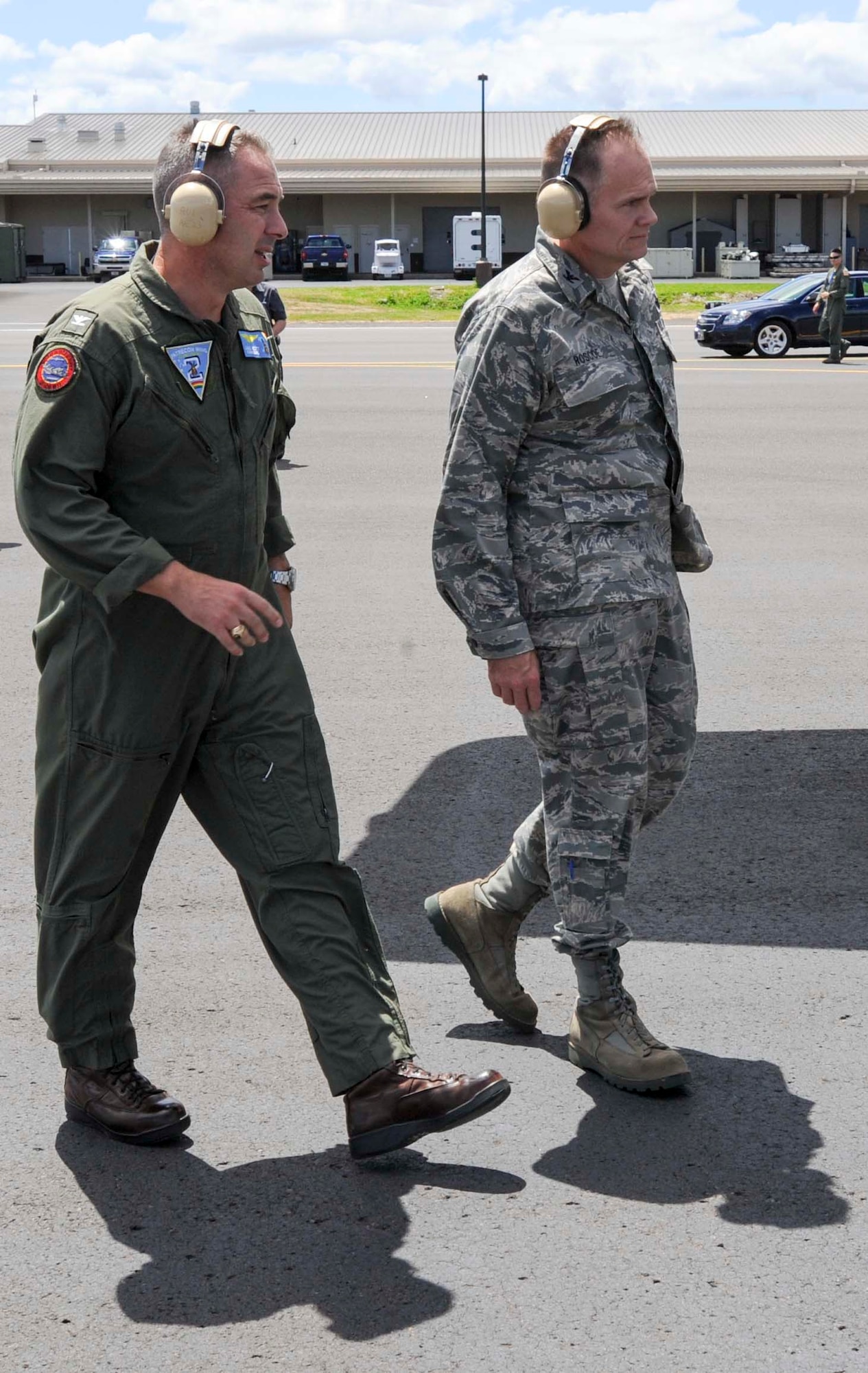 Navy Capt. Lance Scott, commander, Patrol and Reconnaissance Wing Two, (left) walks with Col. Johnny Roscoe, 15th Wing commander, to meet a Navy P-3C Orion aircraft as it lands on the flightline at Joint Base Pearl Harbor-Hickam, Hawaii, Aug. 23, 2013. The aircraft is one of 11 P-3s, two Hawkers and three VR-51s aircraft that will temporarily relocate from Marine Corps Base Hawaii to JBPH-H because of runway construction. (U.S. Air Force photo/Staff Sgt. Terri Paden)