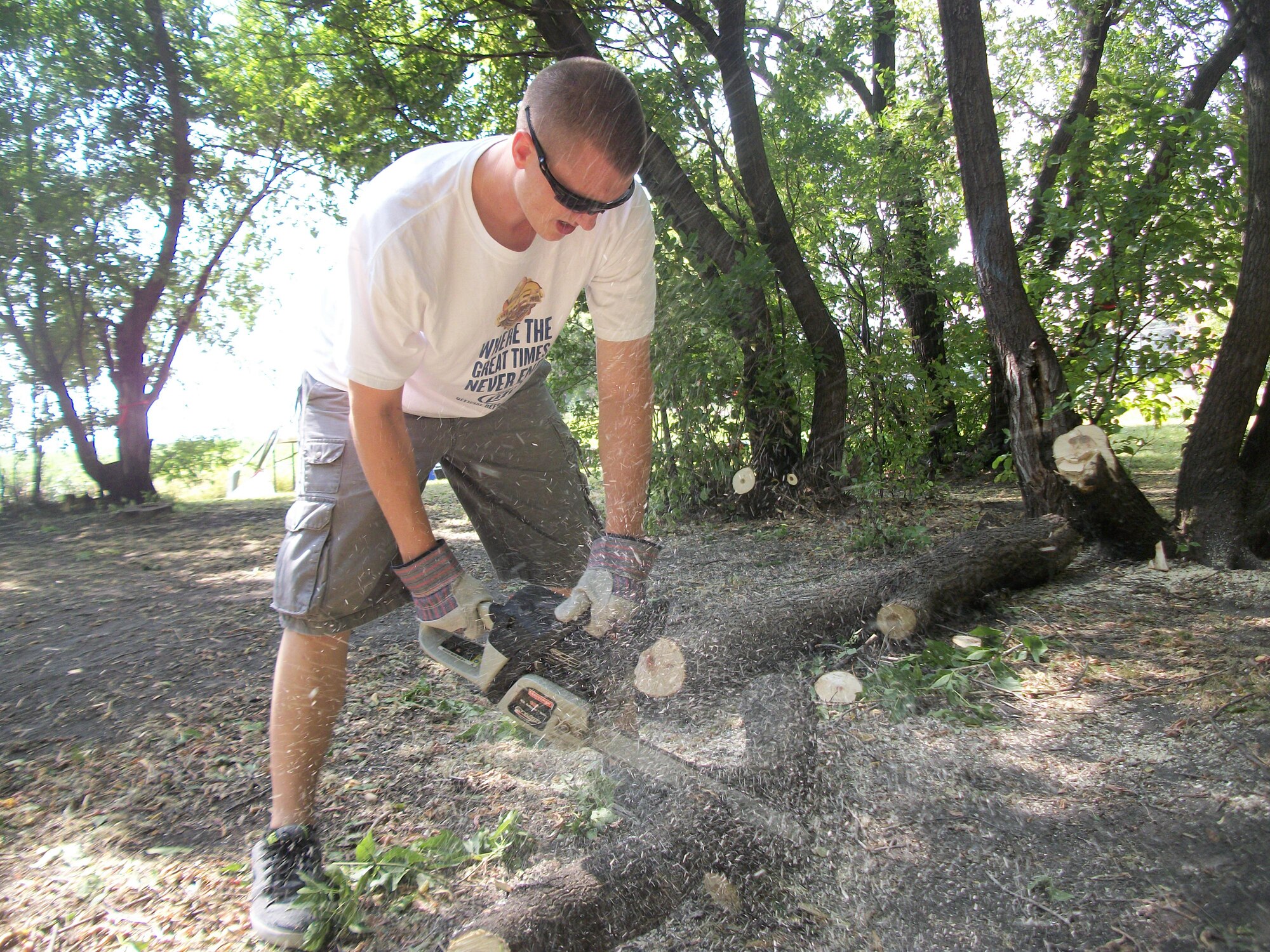 Senior Airman Jordan Warnke, saws another tree trunk into smaller pieces at Seebart Park in Emerado, N.D., on Aug. 24, 2013. Warnke was one of seven Warriors of the North from Grand Forks Air Force Base, N.D., who volunteered to help do some landscaping as part of a beautification project for the park in the nearby town.(U.S. Air Force photo/Staff Sgt. Luis Loza Gutierrez)

