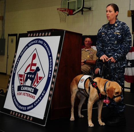 Chief Petty Officer Jeannette Tarqueno, a gunner’s mate and wounded warrior, addresses the audience with her new service dog Gaza, during a ceremony Aug. 26, 2013, at the Naval Consolidated Brig Charleston, S.C. Gaza was trained by NCBC prisoners in conjunction with Carolina Canines for Service, a non-profit organization that trains service dogs for veterans with disabilities. Gaza, a Labrador retriever, will assist Tarqueno by providing more independence and comfort in her life. (U.S. Air Force photo/ Airman 1st Class Chacarra Neal)