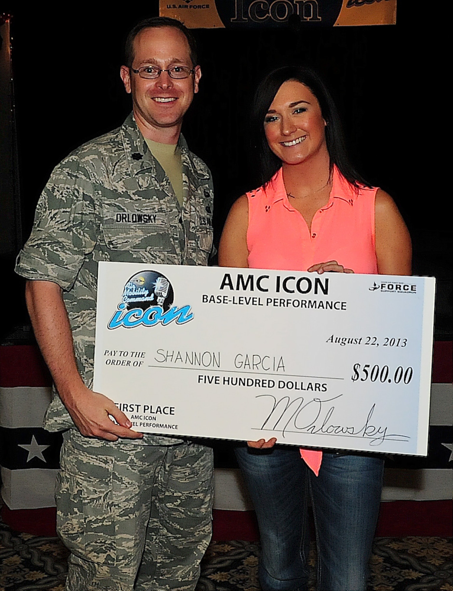 Shannon Garcia, spouse of Airman 1st Class Tyler Garcia, receives the 1st place check from Lt. Col. Matthew Orlowsky, 436th Force Support Squadron commander, at the Air Mobility Command Icon qualifier Aug. 22, 2013, on Dover Air Force Base, Del. Garcia performed against 10 other competitors. (U.S. Air Force photo/Airman 1st Class Ashlin Federick)