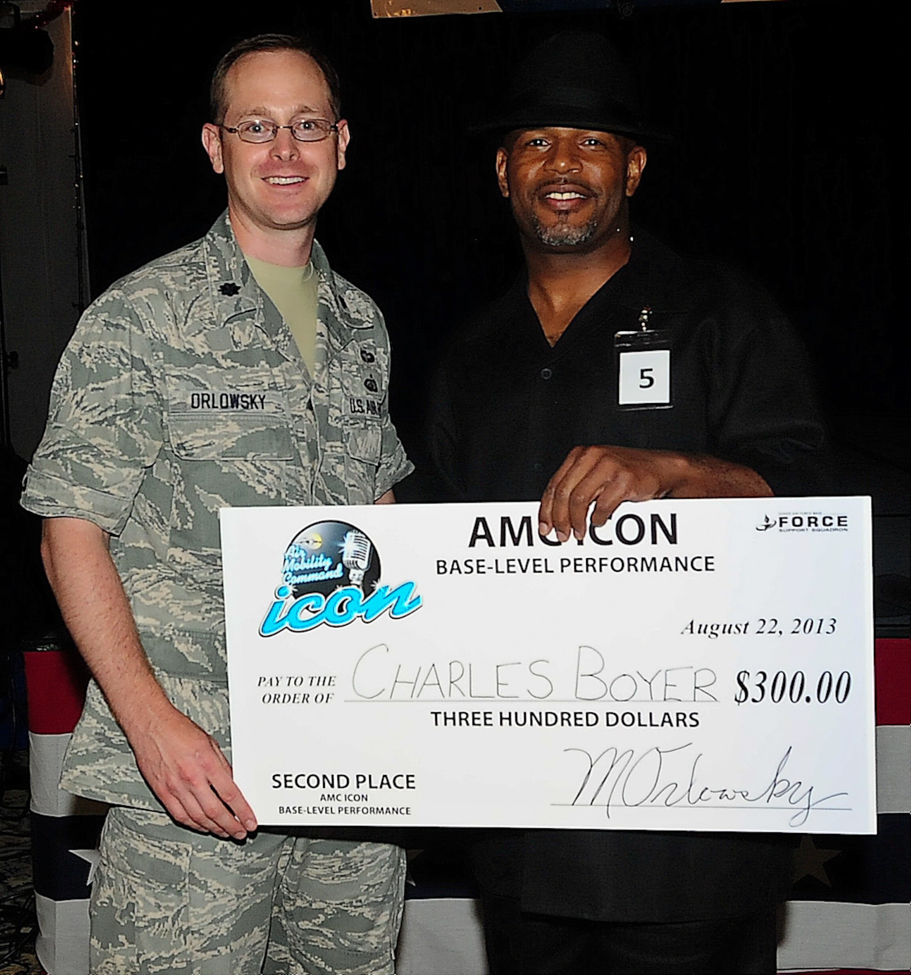 Senior Master Sgt. Charles Boyer, 512th Maintenance Group, receives the 2nd place check from Lt. Col. Matthew Orlowsky, 436th Force Support Squadron commander, at the Air Mobility Command Icon qualifier Aug. 22, 2013, on Dover Air Force Base, Del. Eleven Team Dover members competed to represent Dover AFB at the AMC Icon competition judged by personnel from Scott Air Force Base, Ill. (U.S. Air Force photo/Airman 1st Class Ashlin Federick)