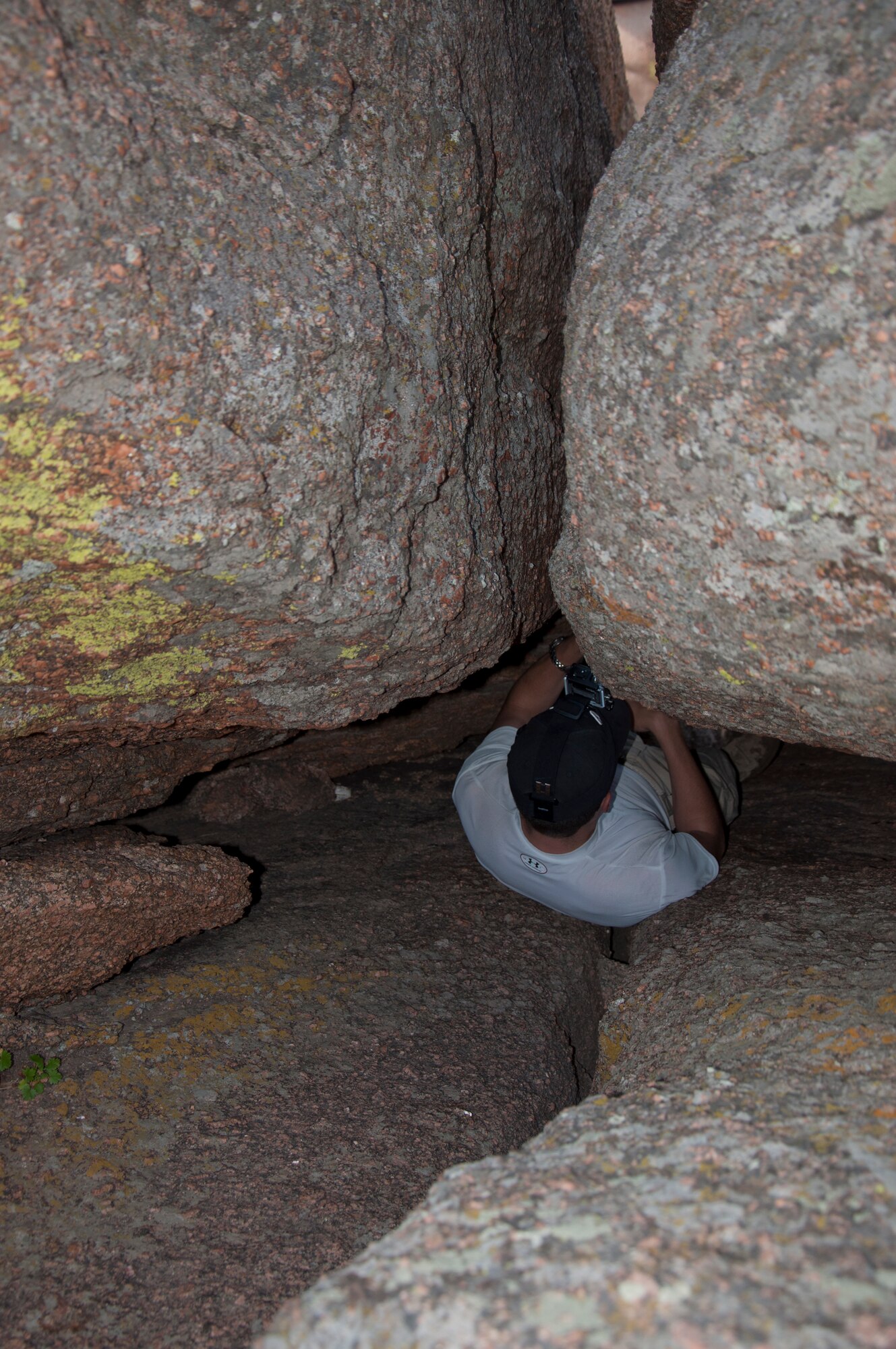 130824-F-GZ967-035 Airman 1st Class Cameron Dooley, 90th Comptroller Squadron customer service technician, scouts out a tight path through a tunnel in the hills of Vedauwoo, Wyo., Aug. 24, 2013. Dooley was part of a group of Airmen who went out hiking as a way to escape the dorms and be outside. (U.S. Air Force photo by Airman 1st Class Brandon Valle)
