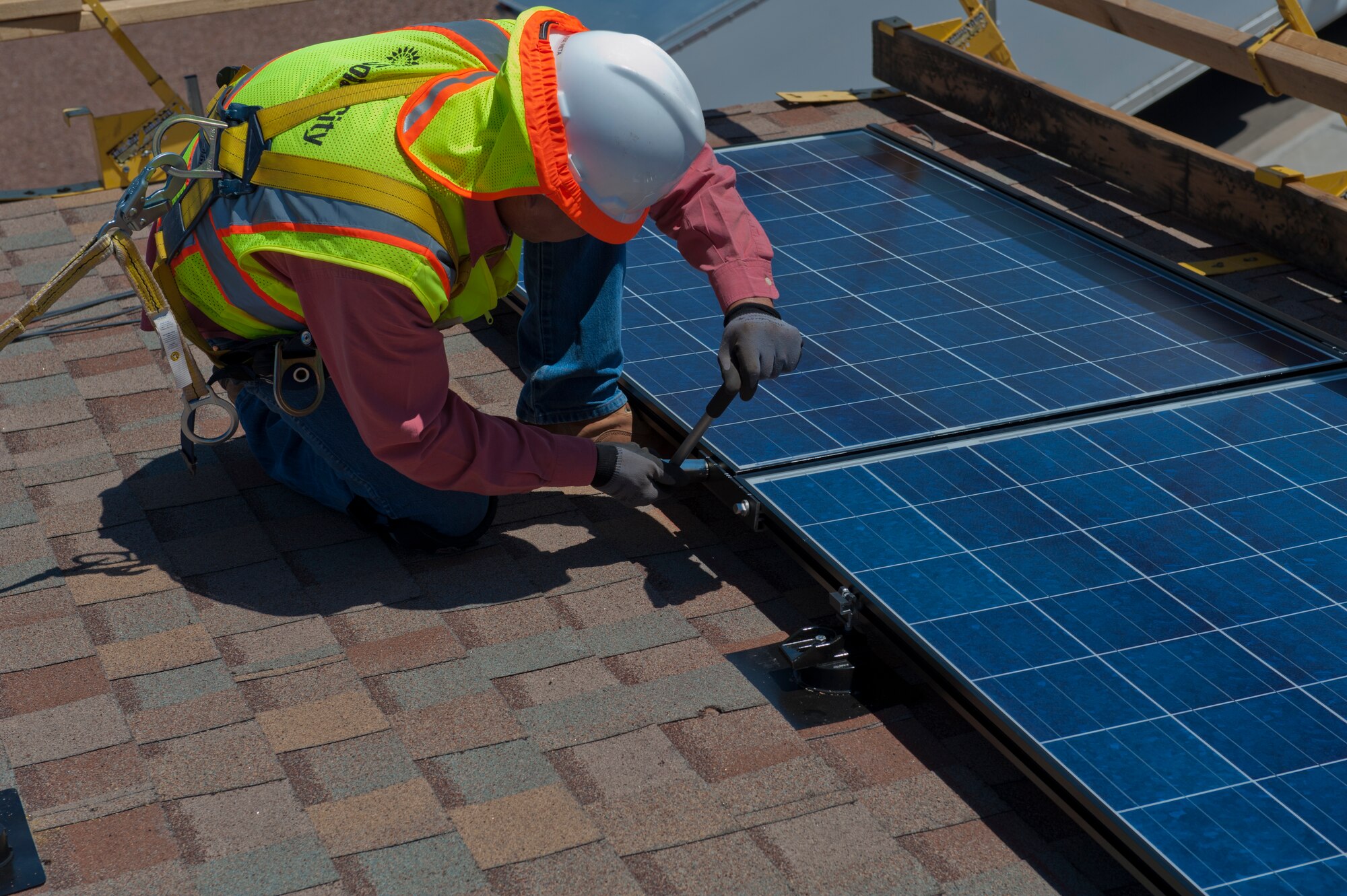 A worker wrenches a panel to the support structure of a home at Holloman AFB, N.M., August 9th. Homes will be selected based on the amount of sun they receive, the condition of the roof and location of surrounding trees. The installation will potentially reduce the cost per kilowatt hour of energy by almost half. Compared to fossil fuels which release greenhouses gases, carcinogens and carbon dioxide; solar cells don't release any harsh chemicals into the air. (Courtesy Photo)