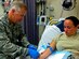 U.S. Air Force Col. John J. Allen Jr., 633rd Air Base Wing commander, draws blood from Master Sgt. Beverly Lutz, 633rd Medical Operations Squadron Emergency Services flight chief, at U.S. Air Force Hospital Langley at Langley Air Force Base, Va., Aug. 6, 2013. Allen learned skills required of all emergency technicians while touring the hospital's facilities. (Courtesy photo/Released)