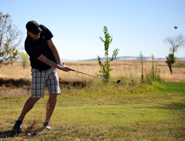 1st Lt. Joseph Simms, 9th Force Support Squadron sustainment flight commander, strikes a golf ball during a fundraising golf tournament at Beale Air Force Base, Calif., on Aug. 23, 2013. The tournament raised money for the Air Force Ball to be held on Sep. 21, 2013. (U.S. Air Force photo by Airman 1st Class Bobby Cummings/Released)
