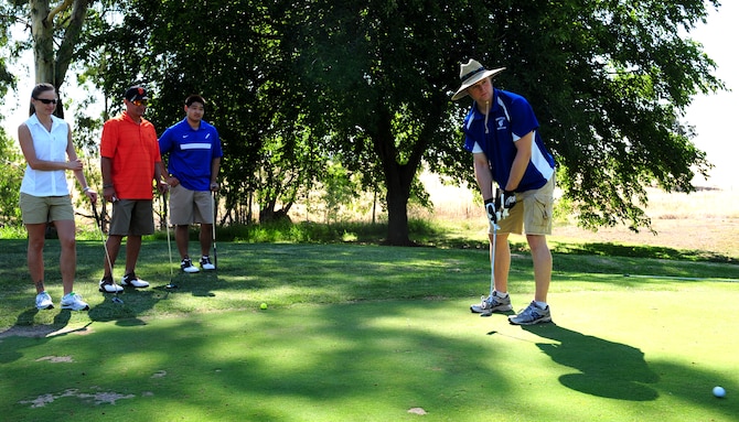 1st Lt. Joshua Larson, 9th Communications Squadron chief network control center chief, putts on hole 10 during a fundraising golf tournament for the Air Force Ball at Beale Air Force Base, Calif., on Aug. 23, 2013. Behind Larson are his team members for the tournament. (U.S. Air Force photo by Airman 1st Class Bobby Cummings/Released)