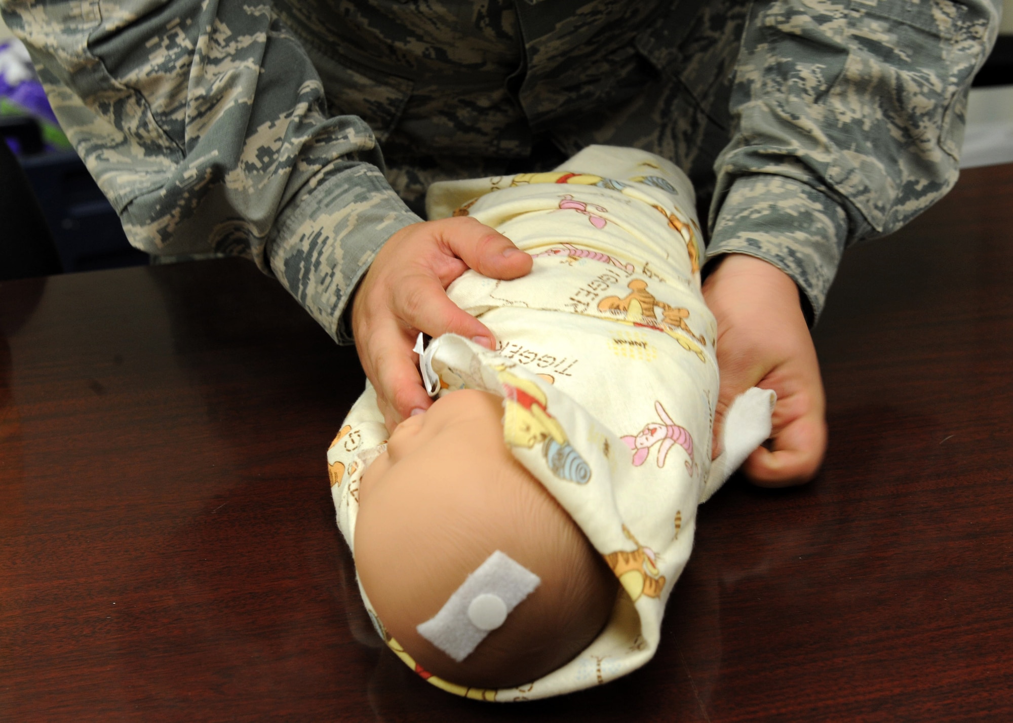U.S. Air Force Senior Airman Jack Bragg, 7th Communications Squadron, wraps a pretend baby in a blanket during a Dad’s 101 class Aug. 22, 2013, at Dyess Air Force Base, Texas. Dad’s 101 provides expectant fathers hands-on experience on how to care for a new baby. (U.S. Air Force photo by Airman Autumn Velez/Released)