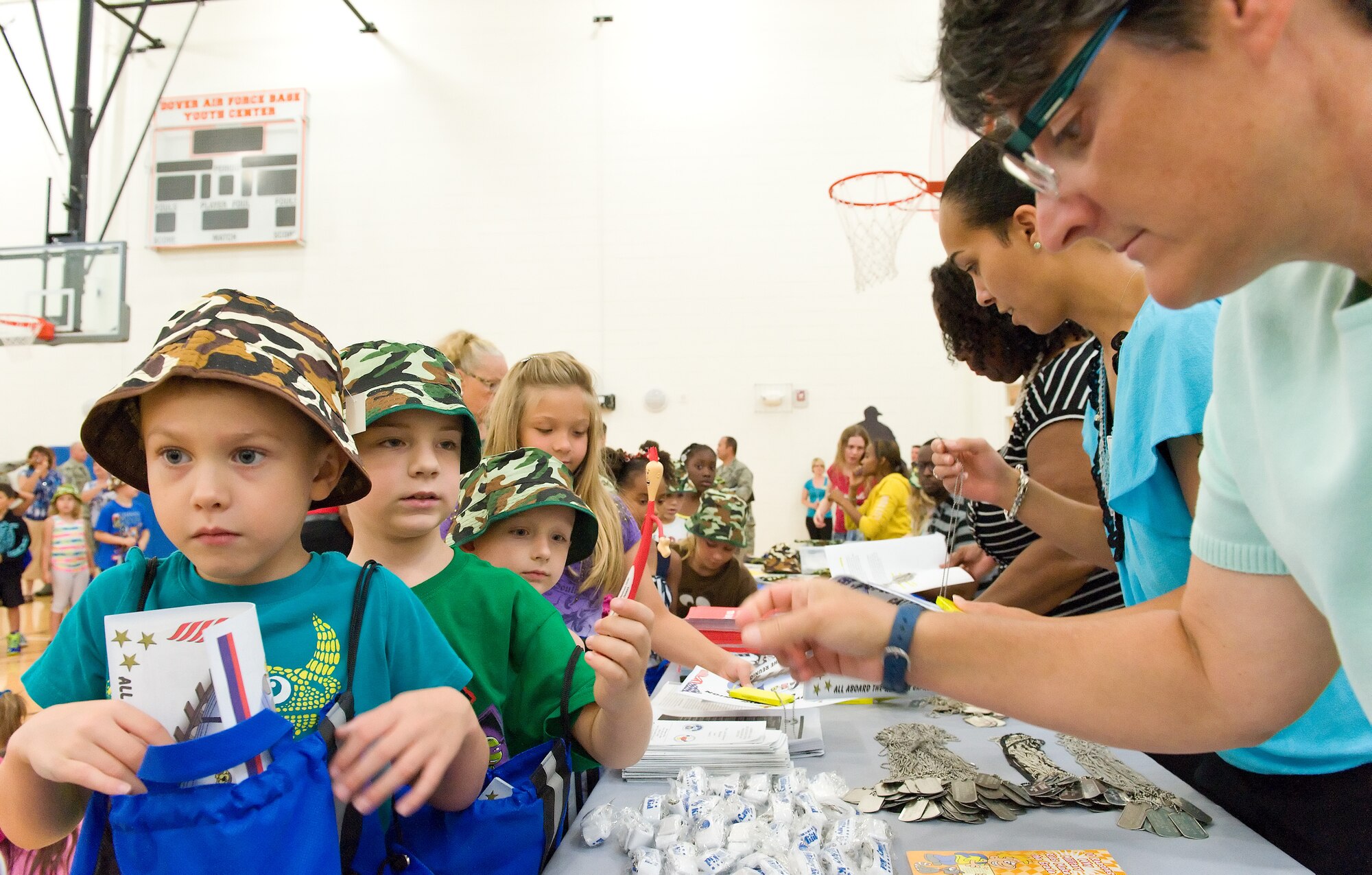 Members of the Airman & Family Readiness Center hand out free gifts to children in the children's mobility line August 22, 2013, at Dover Air Force Base, Del. More than 350 children participated in the event, which simulated mobility line processing. (U.S. Air Force photo/Roland Balik)