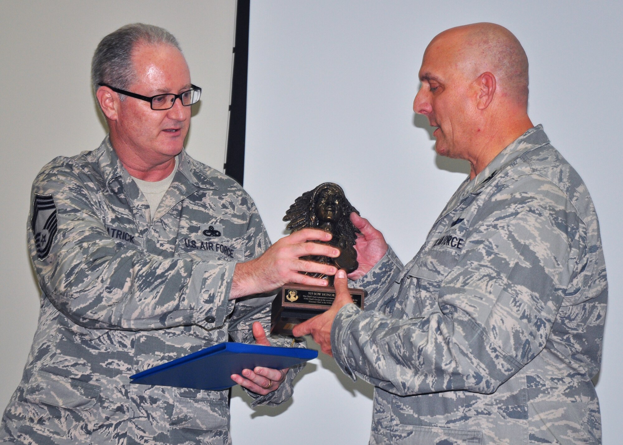 Chief Master Sgt. Jeffrey Fitzpatrick from the 919th Maintenance Squadron , left, presents the Chief’s bust to Col. Andy Comtois, outgoing 919th Special Operations Wing commander, during Comtois’s farewell gathering Aug. 23 at Duke Field.   Duke’s Chiefs Group inducted Comtois as an honorary chief master sergeant to honor his leadership support for the wing’s reservist Airmen.  Comtois has accepted a new assignment as commander of the Joint Special Operations Air Component for Special Operations Command Africa.  U.S. Air Force photo/Dan Neely)