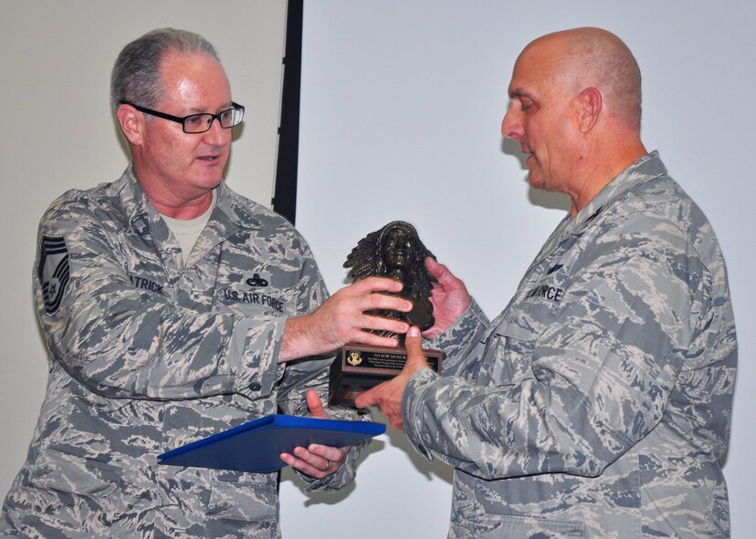 Chief Master Sgt. Jeffrey Fitzpatrick from the 919th Maintenance Squadron , left, presents the Chief’s bust to Col. Andy Comtois, outgoing 919th Special Operations Wing commander, during Comtois’s farewell gathering Aug. 23 at Duke Field.   Duke’s Chiefs Group inducted Comtois as an honorary chief master sergeant to honor his leadership support for the wing’s reservist Airmen.  Comtois has accepted a new assignment as commander of the Joint Special Operations Air Component for Special Operations Command Africa.  U.S. Air Force photo/Dan Neely)