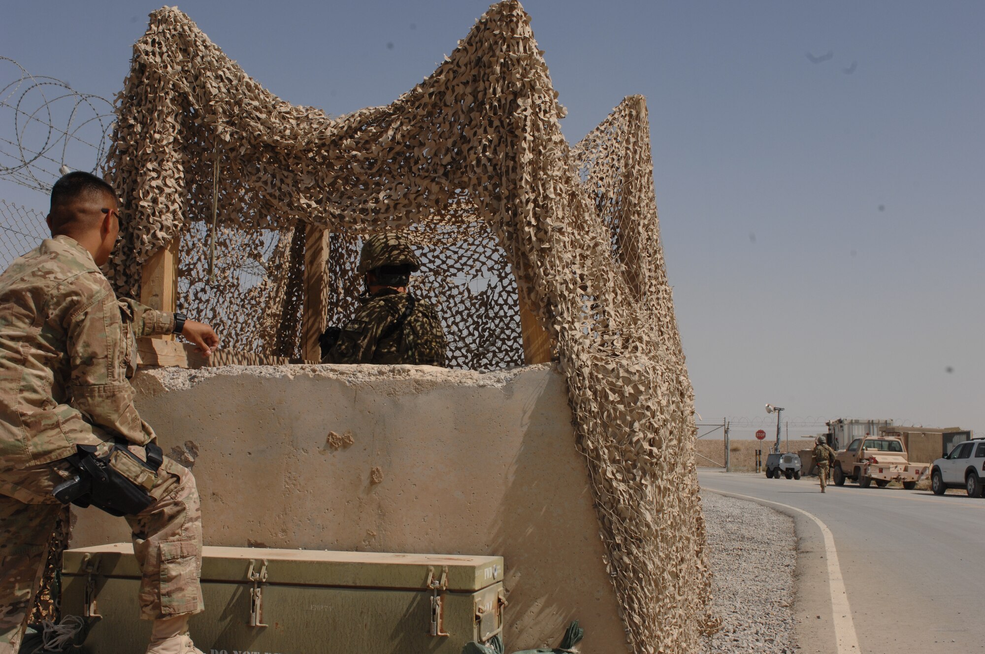 An Airmen from the 451st Expeditionary Maintenance Squadron Munitions Flight answers force protection questions while another rushes to secure a gate during a force protection exercise at  Kandahar Airfield, Afghanistan, Aug. 22, 2013. Force protection procedures provide guidance for Airmen during crises. (U.S. Air Force photo by Senior Airman Jack Sanders)   