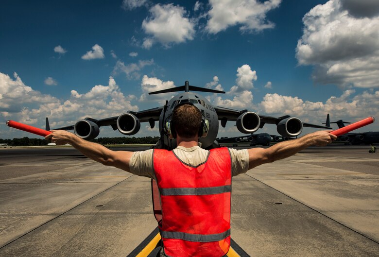 Senior Airman Cody Richman, 437th Aircraft Maintenance Squadron C-17 Globemaster III flying crew chief, marshals a C-17 into place Aug. 12, 2013, at Joint Base Charleston – Air Base, S.C. Richman’s ensures the aircraft is working properly and safe to fly at a moment’s notice. (U.S. Air Force photo/ Senior Airman Dennis Sloan)