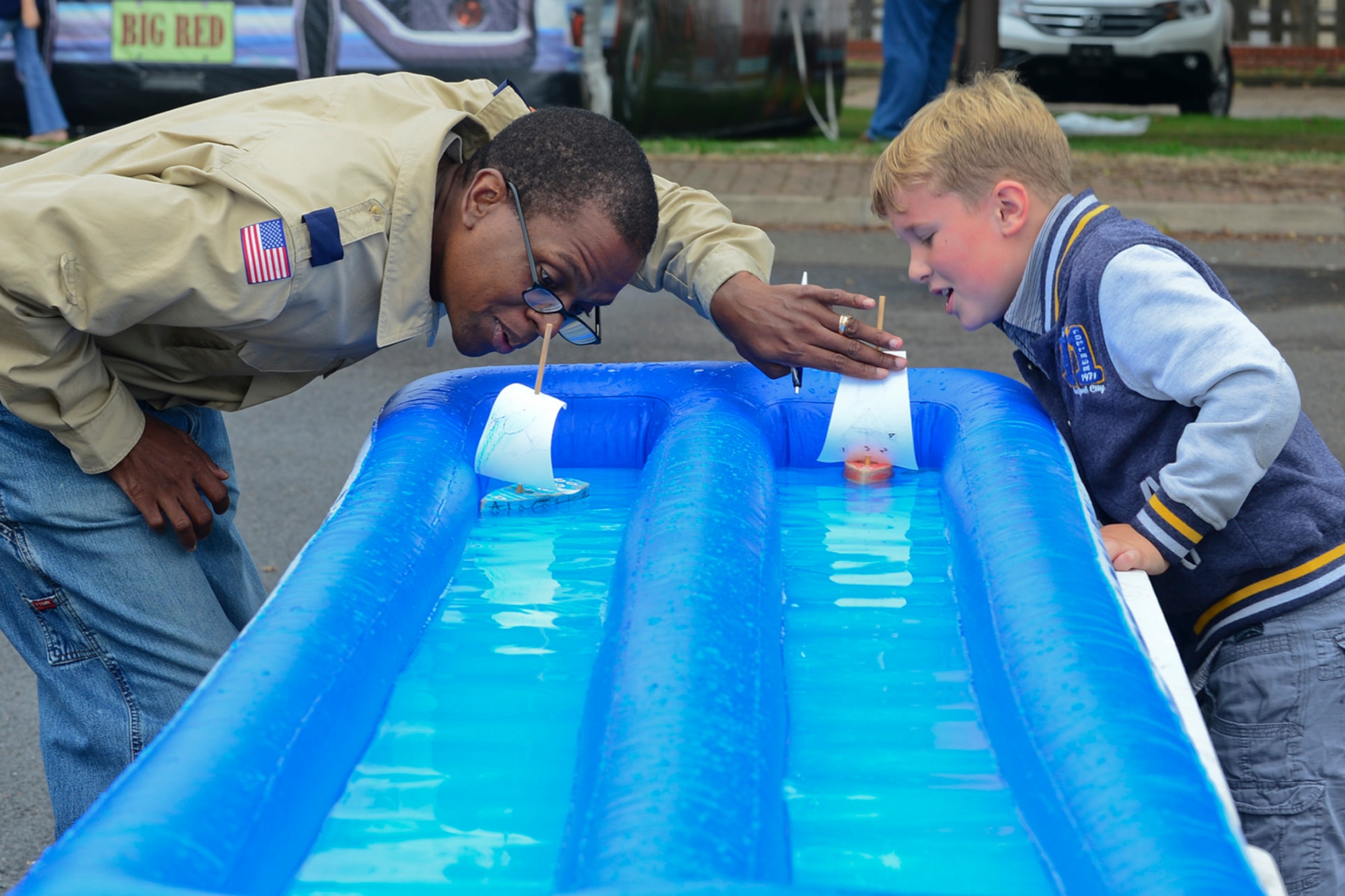 Tech. Sgt. Herman Jackson, 100th Force Support Squadron dining facility manager from Royal Air Force Mildenhall, England, races sail boats against Logan Hutton, son of Tech. Sgt. Keith Hutton, 48th Civil Engineer Squadron Fire Department assistant chief, at RAF Lakenheath, England, Aug. 24, 2013. A scouting recruitment fair was held at RAF Lakenheath, for children and prospective volunteers interested in joining Boy, Girl or Cub Scouts. (U.S. Air Force photo by Airman 1st Class Dana J. Butler/Released)