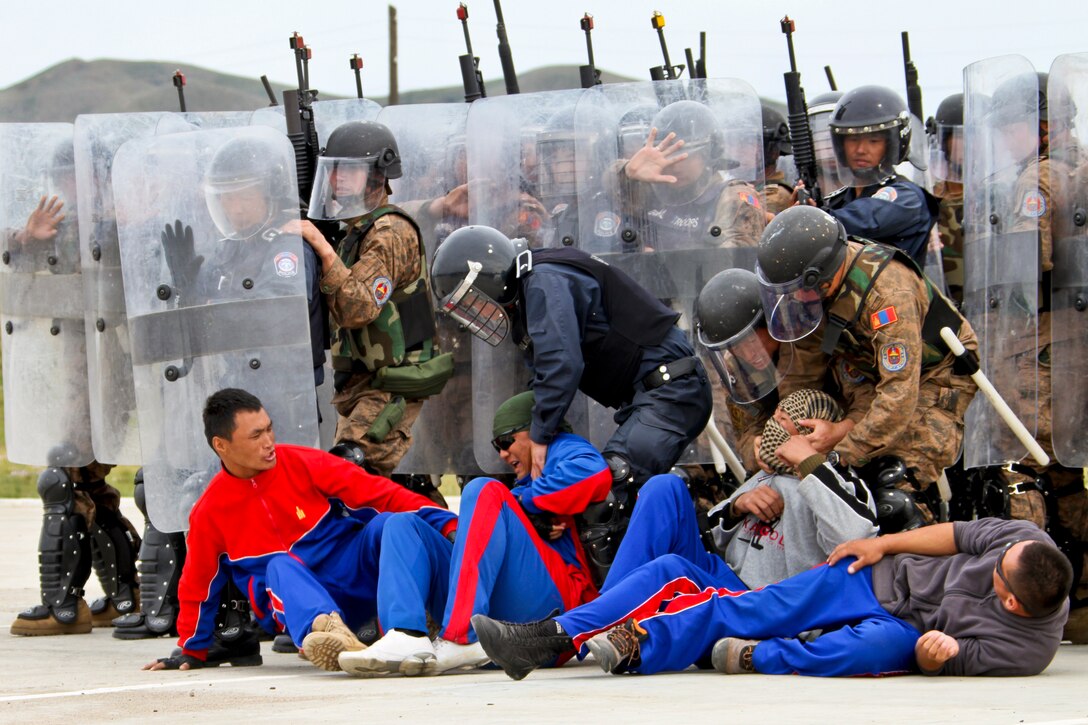 Mongolian armed forces service members and general police demonstrate riot control techniques during the opening ceremony of the seminar portion of Nonlethal Weapons Executive Seminar in Five Hills Training Area, Mongolia, Aug. 26, 2013. NOLES is a regularly scheduled field training exercise and leadership seminar sponsored annually by U.S. Marine Corps Forces Pacific, and it is designed to promote awareness and effective use of nonlethal weapons as a tool to maintain order in low-intensity or civil unrest situations. U.S. Marine Corps photo by Sgt. John M. Ewald
