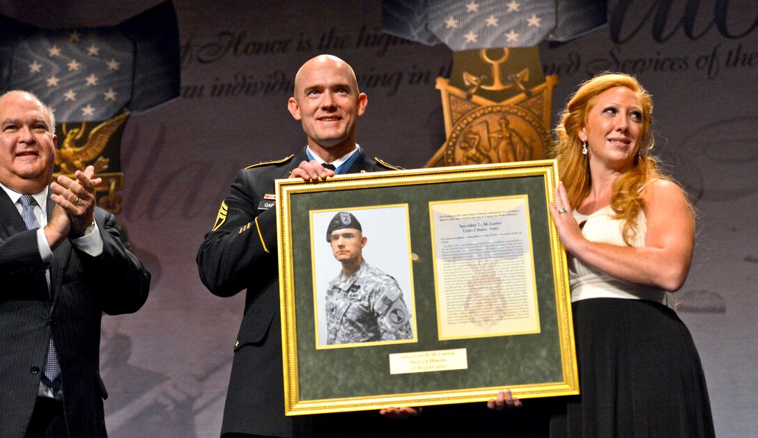 Medal of Honor recipient Army Staff Sgt. Ty Michael Carter and his wife, Shannon, receive a plaque as he is honored during a ceremony at the Pentagon, Aug. 27, 2013, as Joseph W. Westphal, undersecretary of the Army, looks on.