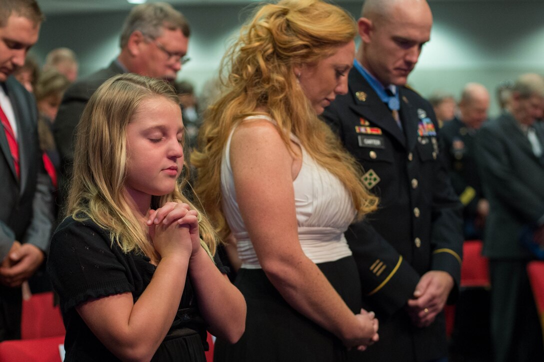 Army Staff Sgt. Ty Michael Carter and his family bow their heads in prayer during a Medal of Honor Hall of Heroes induction ceremony at  the Pentagon, Aug. 27, 2013.