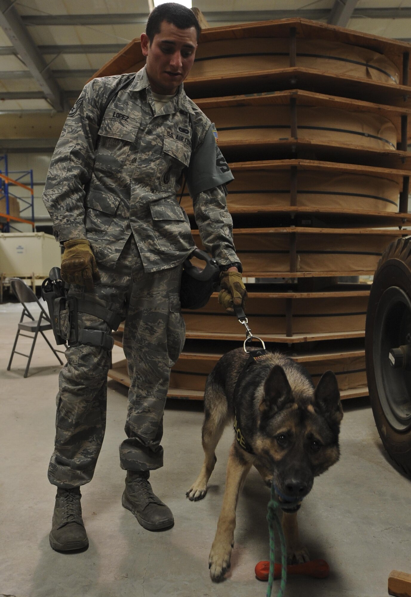 Mayo, 380th Expeditionary Security Forces Squadron military working dog, bites on his reward given to him by Staff Sgt. Justin Lopez, 380th ESFS MWD handler, after searching for explosives or narcotics during training in a warehouse at an undisclosed location in Southwest Asia Aug. 8, 2013. The training was designed to test the MWD’s senses for detecting explosives or narcotics in different quantities. Lopez and Mayo are deployed from Luke Air Force Base, Ariz.