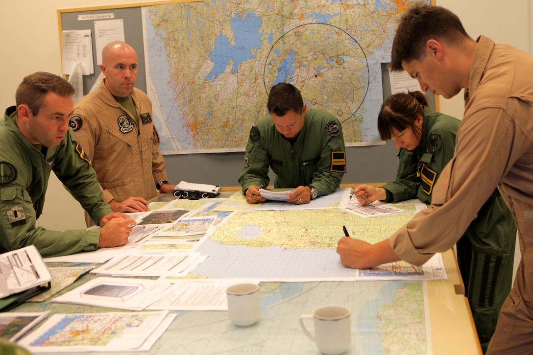 The rotary-wing team, consisting of Marine aviators from Marine Aviation Weapons and Tactics Squadron One, Yuma, Ariz., and the Swedish Air Force 21st UH-60 Black Hawk Helicopter Wing review final mission details before a real-world practical application of Close Air Support and Forward Air Controller (Airborne) operations with Swedish Saab JAS-39 Gripen fighter jets and Swedish Army artillery. Marine aviation instructors from Marine Aviation Weapons and Tactics Squadron One, Yuma, Ariz., introduced Forward Air Controller (Airborne) and Close Air Support concepts, tactics, and procedures for evaluation into the Swedish Air Force’s aviation training with SwAF pilots from the 21st UH-60 Black Hawk Helicopter Wing and the JAS-39 Gripen Operations, Tactics and Evaluations division, August 5-23 at Malmen Military Base, Linköping, Sweden.
