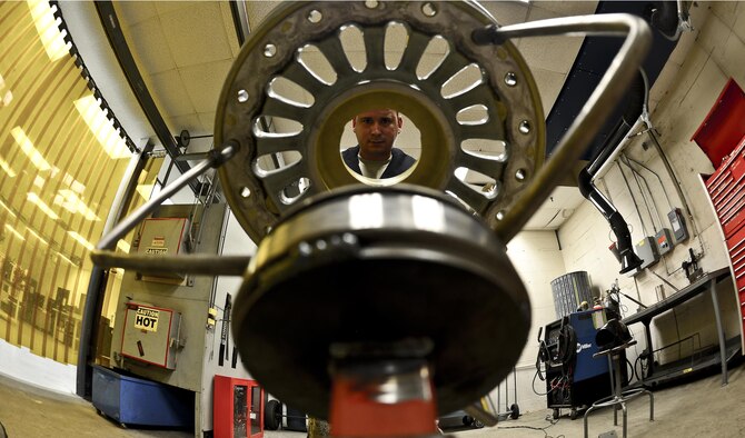 Staff Sgt. Alex Aguayo  inspects a newly fabricated wheel workstation, Aug 20, 2013 at MacDill Air Force Base, Fla. Aguayo is an aircraft metals technician with the 6th Maintenance Squadron who co-engineered a stand to hold the wheel, which reduces the man hours needed to paint by 26 man-hours per set.