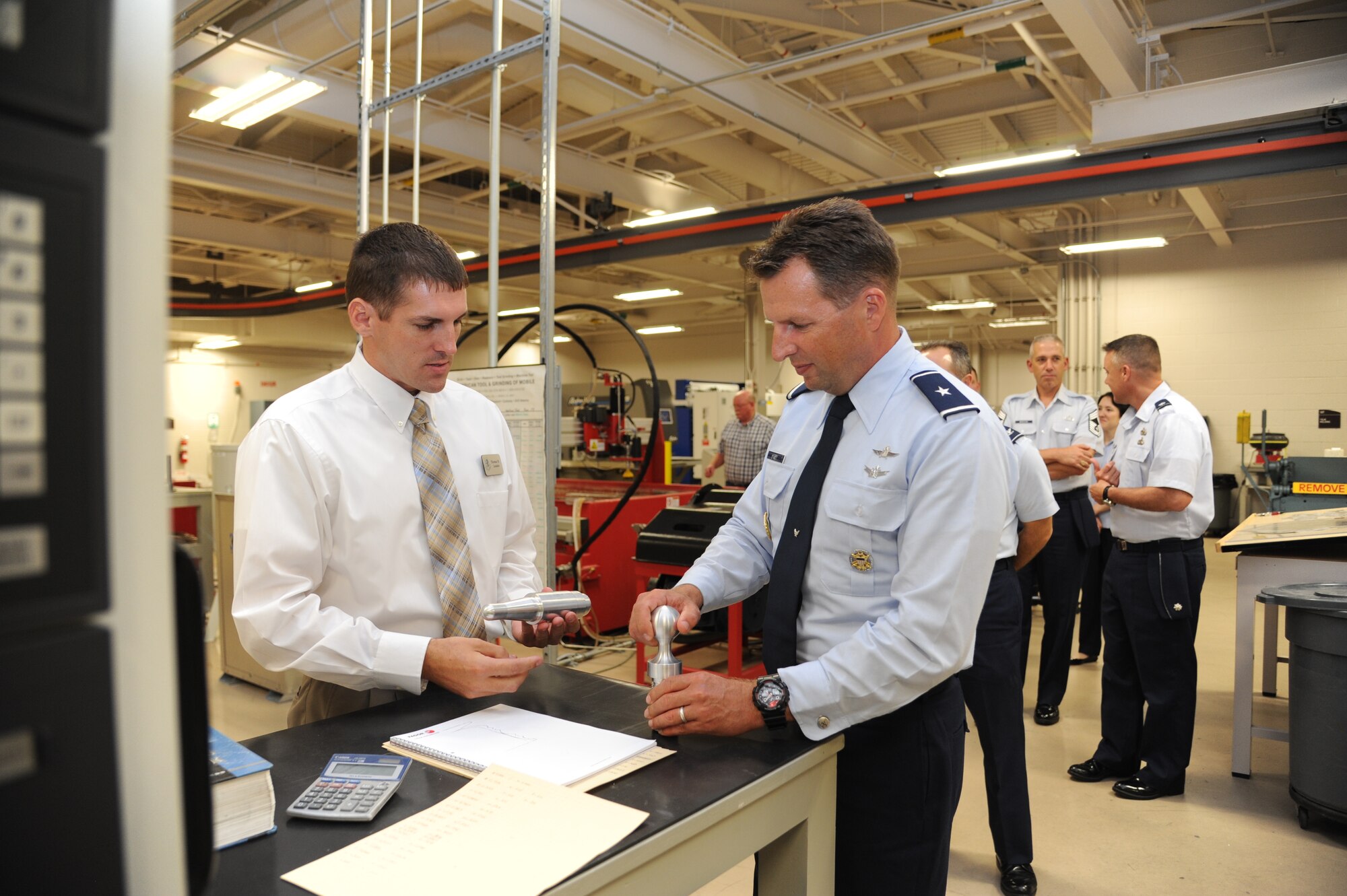 Tomme Lassabe, 81st Training Support Squadron training technology flight chief, shows Brig. Gen. Patrick Higby, 81st Training Wing commander, a sample of close tolerance capabilities obtainable using newly acquired computer numerical controlled machinery in the creation of U.S. Air Force trainers developed by the Trainer Development Center during a two-day immersion tour of the 81st Training Group Aug. 26-27, 2013, Keesler Air Force Base, Miss.  The purpose of the tour was to learn the integration of the group’s mission, operations and personnel.  Higby will continue his tour with the 81st Medical Group, 81st Mission Support Group and Wing Staff Agencies over the next couple of weeks.  (U.S. Air Force photo by Kemberly Groue)