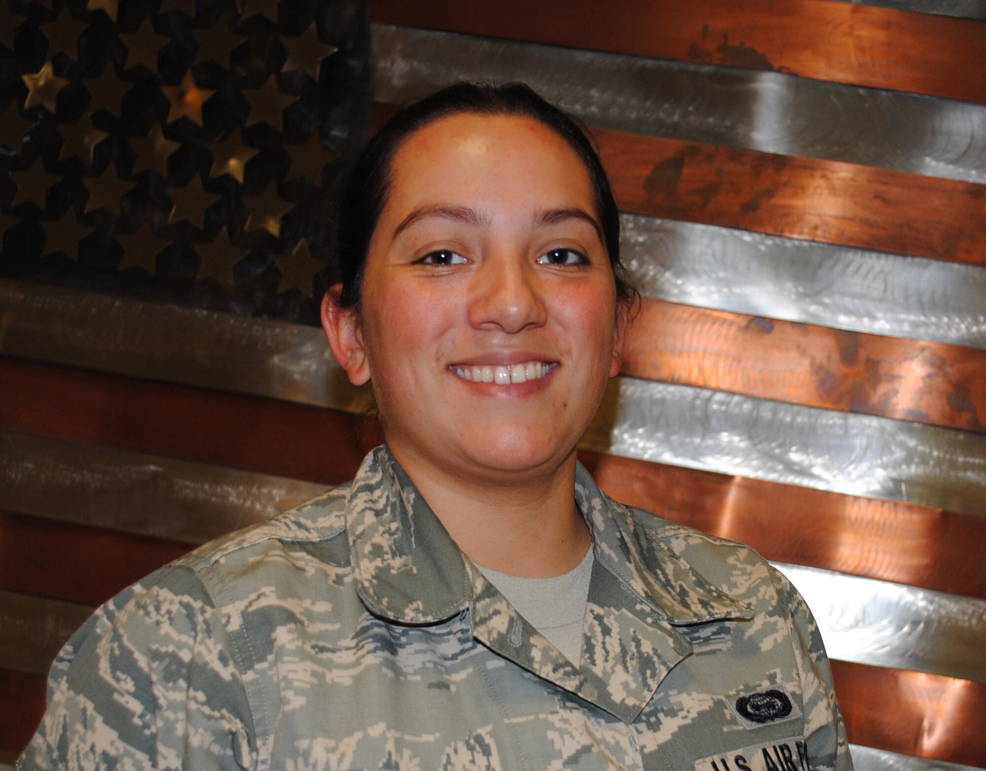 Airman 1st Class Alanna from the 348th Reconnaissance Squadron, poses for a photo in front of a metallic sculpture of a U.S. flag inside Heritage Hall Aug. 9, 2013, on Grand Forks Air Force Base, N.D.  Senior Airman Alanna was recently named Grand Forks AFB’s Warrior of the Week, a selection that recognizes an individual’s hard work and professional. (U.S. Air Force photo/Staff Sgt. Luis Loza Gutierrez) 
