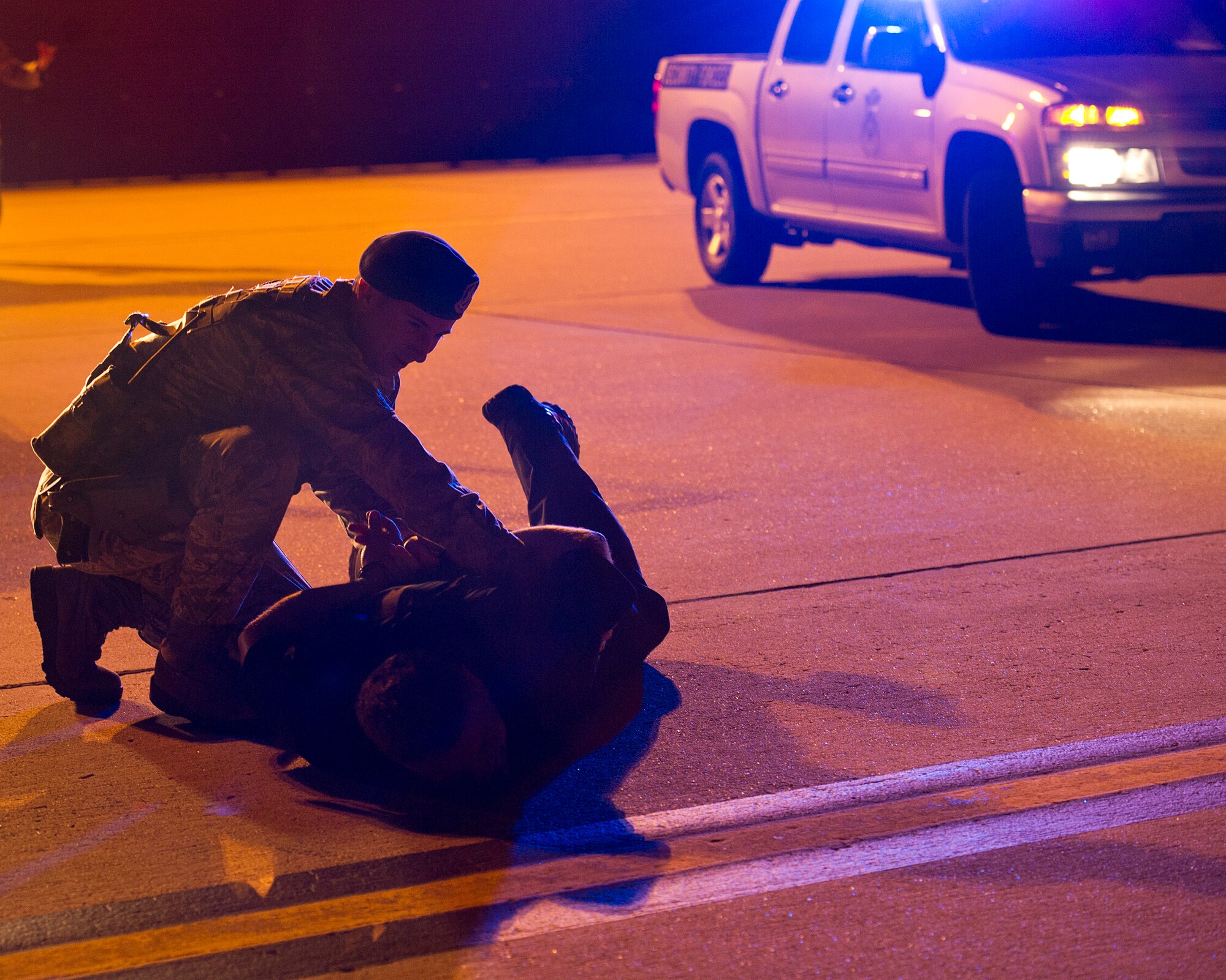 ALTUS AIR FORCE BASE, Okla. -- U.S. Air Force Senior Airman Brenden Marlin, 97th Security Forces Squadron response force patrolman, rolls Nickey Jones, 97th SFS response force patrolman, after restraining his hands, during a simulated security incident on the flightline Aug. 27. The 97th SFS is responsible for guarding the base 24 hours a day. They are one of the various squadrons that work around the clock to ensure mission success at Altus AFB. (U.S. Air Force photo by Senior Airman Kenneth W. Norman / Released)